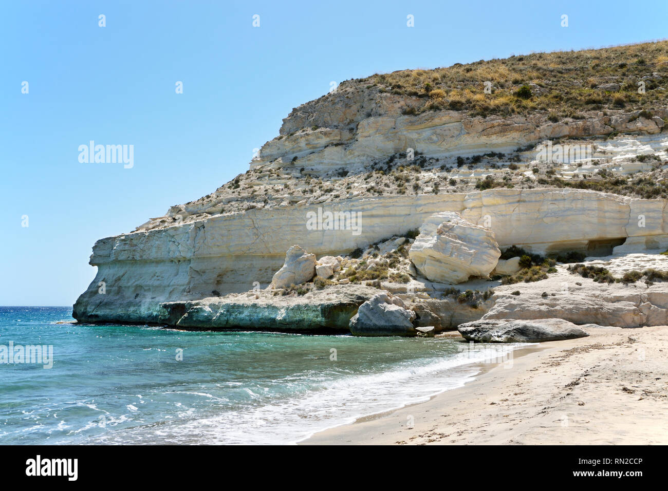 Che circondano la bella cittadina di Agua Amarga nel Parco Naturale Cabo de Gata (Spagna) sono fantastiche scogliere sul mare con grotte scavate nella roccia. Foto Stock