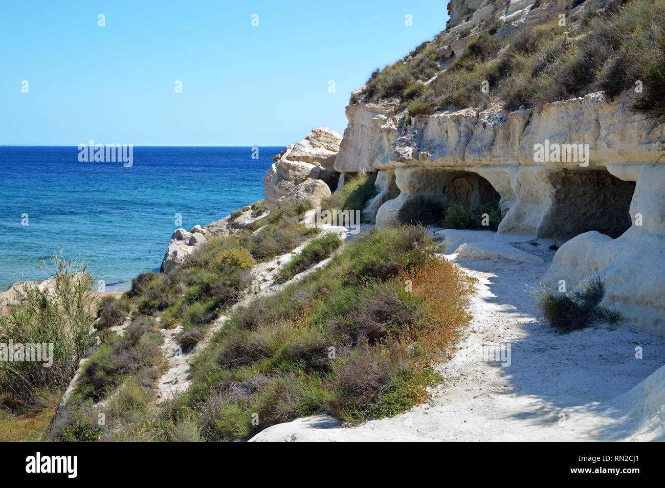 Che circondano la bella cittadina di Agua Amarga nel Parco Naturale Cabo de Gata (Spagna) sono fantastiche scogliere sul mare con grotte scavate nella roccia. Foto Stock