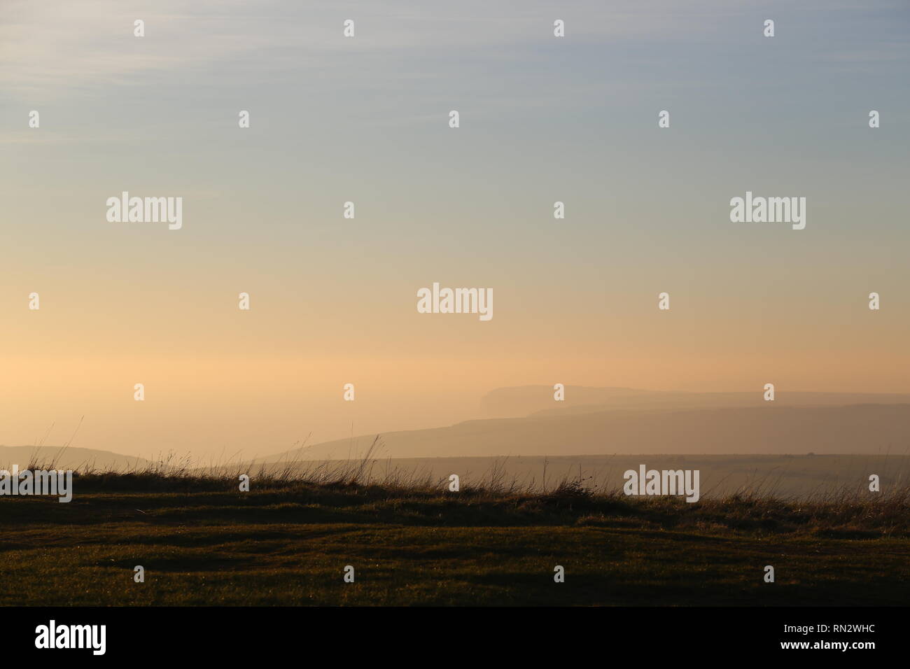 Lontane colline costiere in golden haze Foto Stock