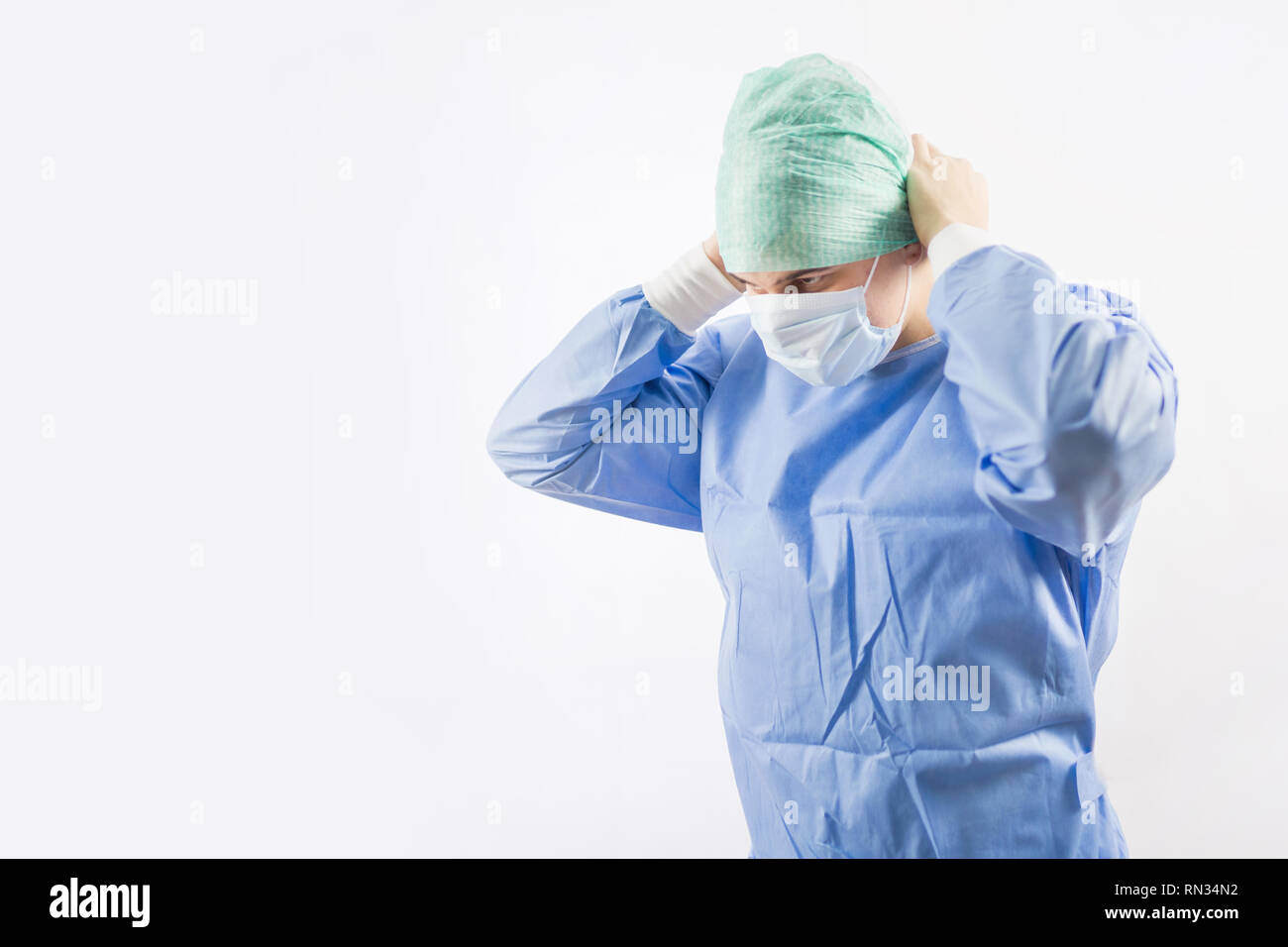 Medico chirurgo in guanti sterili preparando per il funzionamento in ospedale. Indossa il cappuccio chirurgico e abito blu Foto Stock