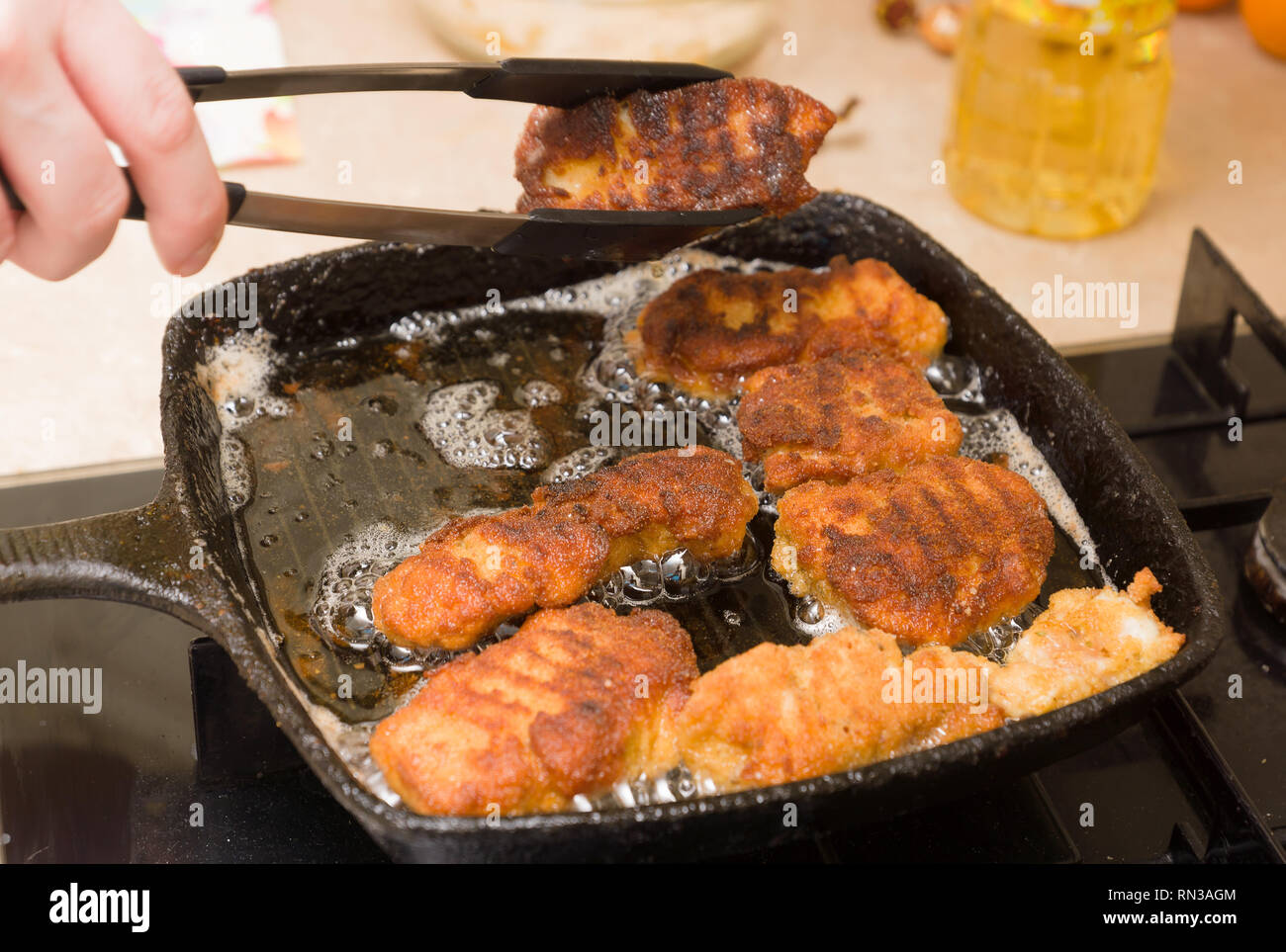 Pepite di cottura da freschi a base di carne di pollo su un caldo cast-padella di ferro Foto Stock
