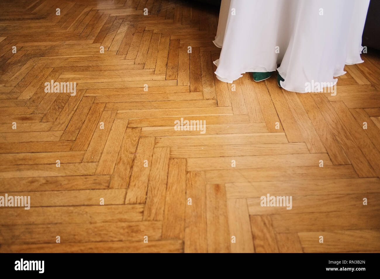 Coulisse di un abito da sposa su uno sfondo di un pavimento in legno con bagliori. Motion Blur. Foto Stock
