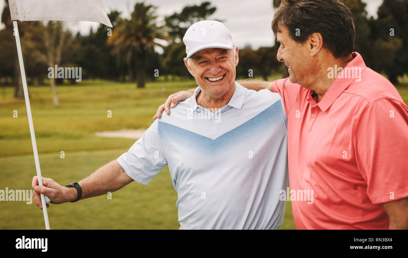 Gli amici del golf sul putting green al golf. Due senior giocatore di golf sul campo da golf in piedi insieme con la bandiera. Foto Stock