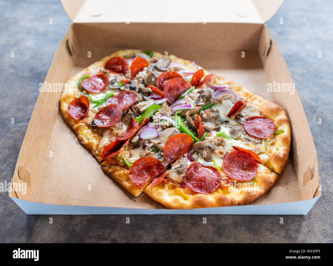 Pizza con diversi condimenti in scatola di consegna Foto Stock