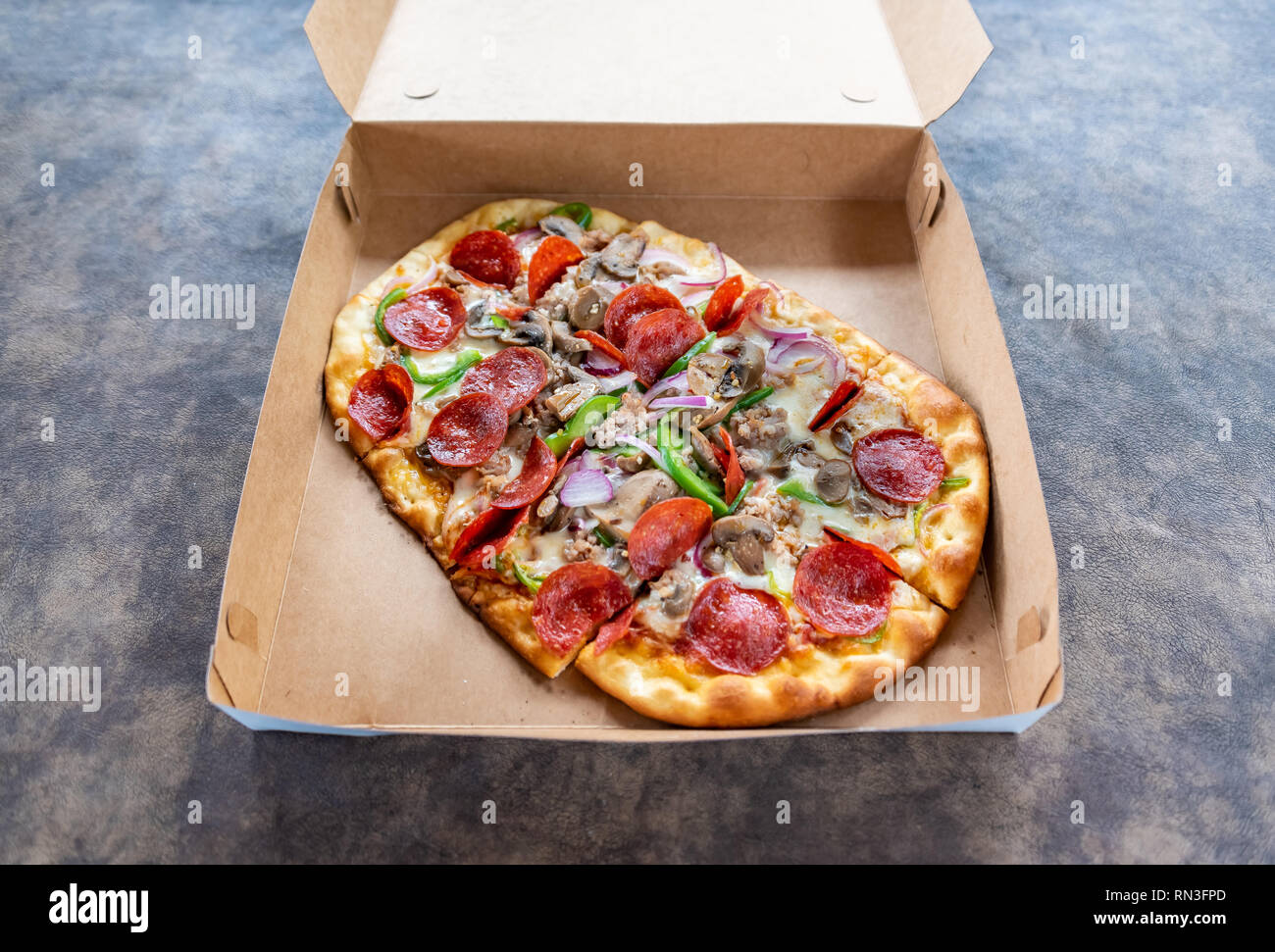 Pizza con diversi condimenti in scatola di consegna Foto Stock