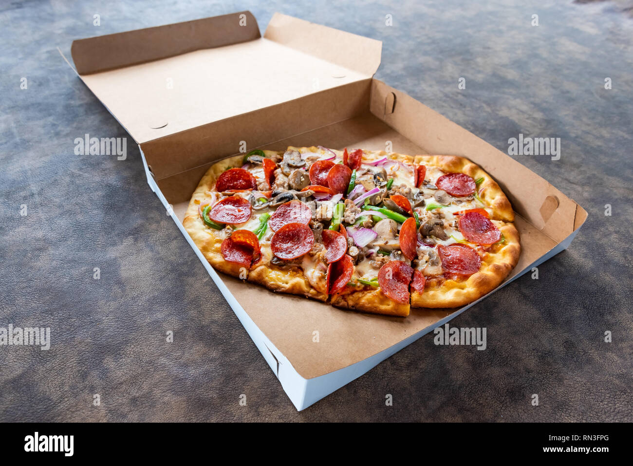 Pizza con diversi condimenti in scatola di consegna Foto Stock