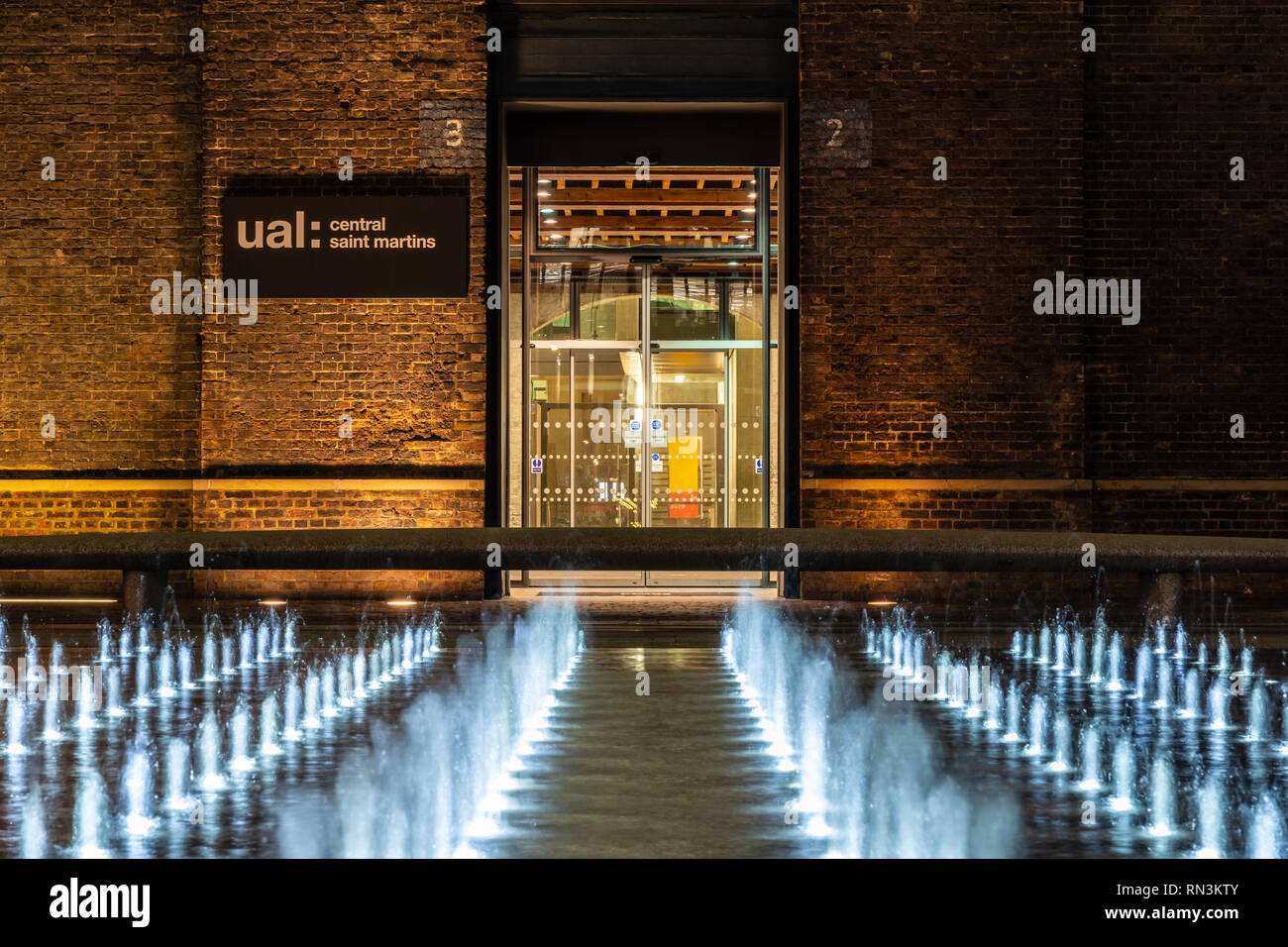 London, England, Regno Unito - 20 dicembre 2018: le fontane sono illuminate di notte in Piazza Grannary fuori Central Saint Martin's College dell'Università degli Foto Stock