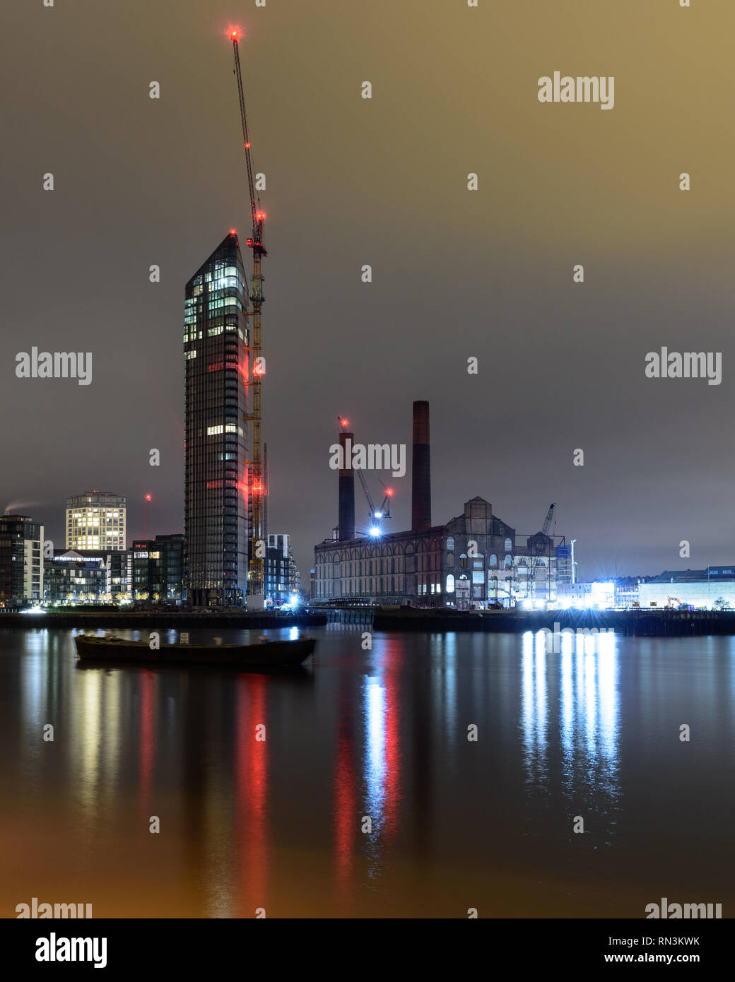 London, England, Regno Unito - 28 dicembre 2018: gru a torre sono illuminate di notte accanto a costruire nuovi edifici di appartamenti e dei derelitti lotti Road stazione di potenza mi Foto Stock