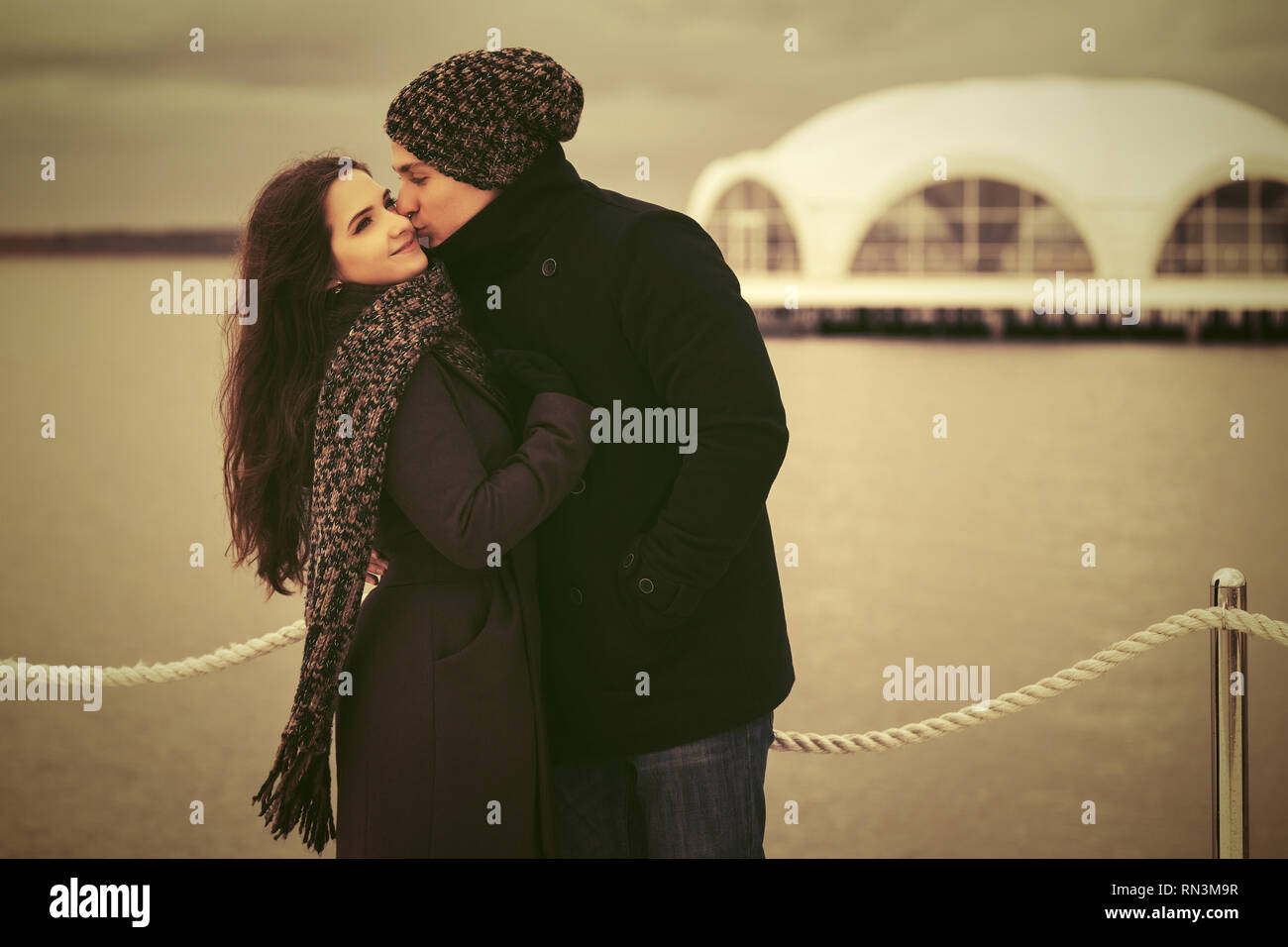 Felice moda giovane coppia in amore kissing outdoor elegante uomo e donna che indossa cappotti classico beanie e sciarpa Foto Stock