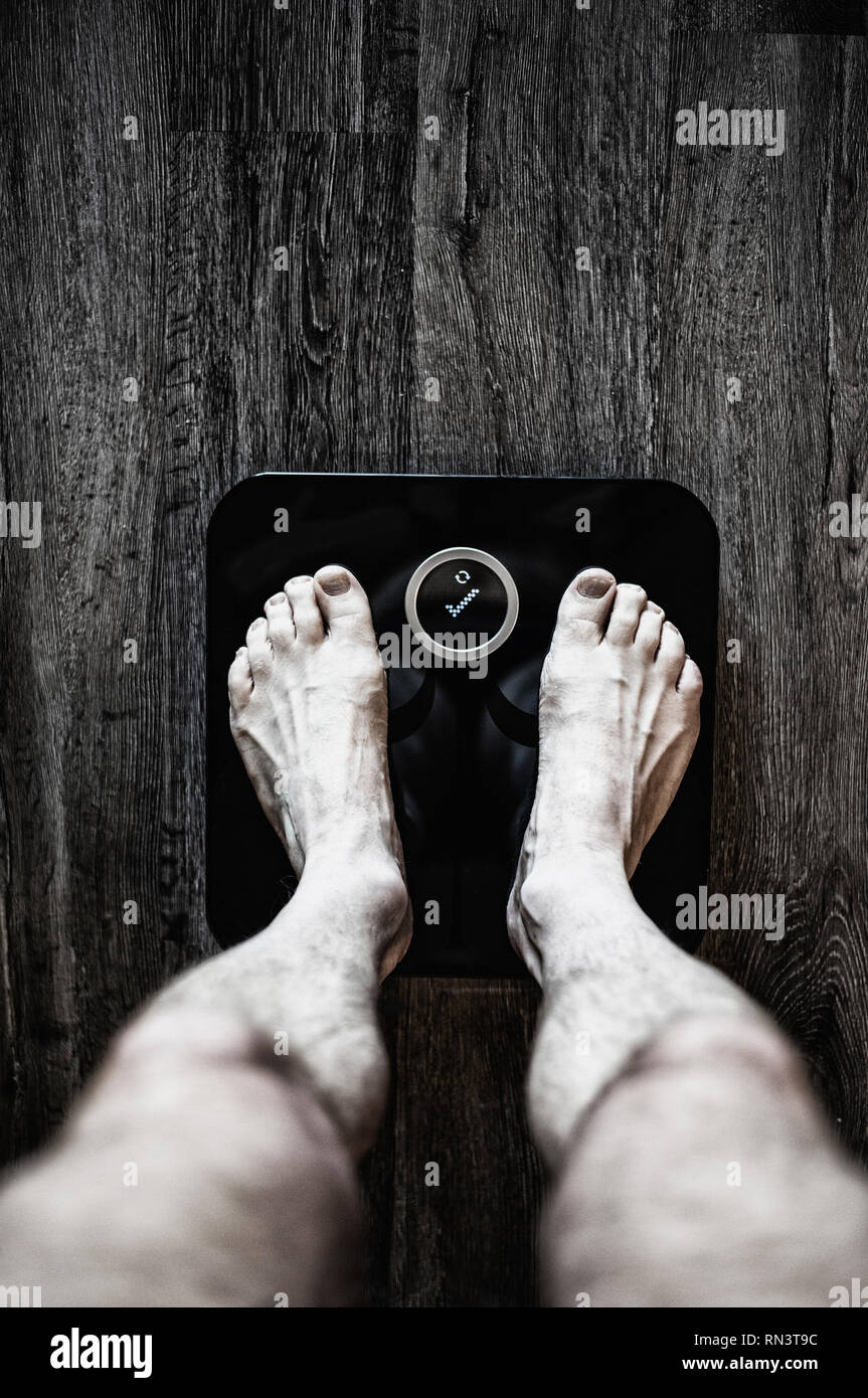 Gambe di uomo con scala di peso Foto Stock