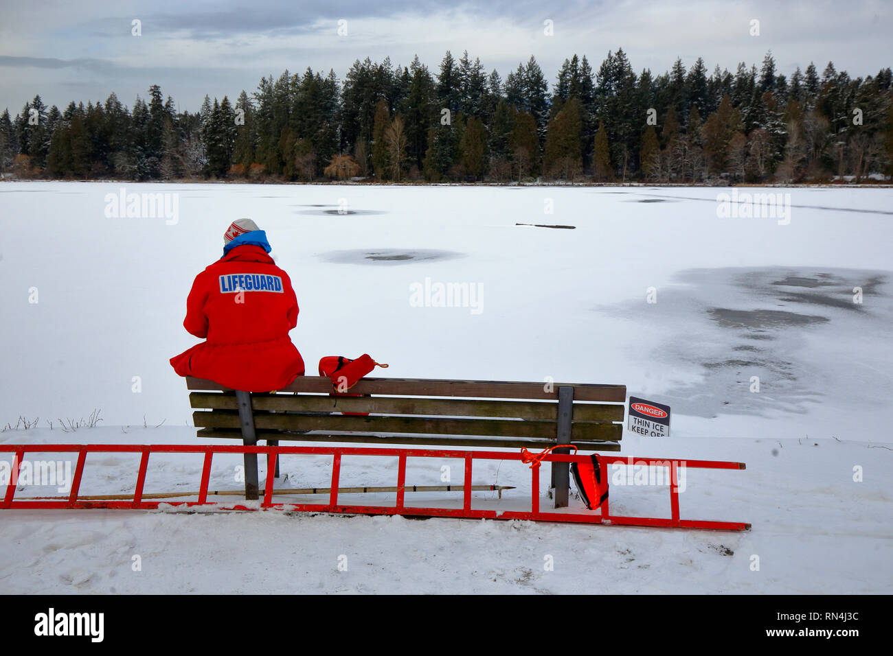 Un bagnino tiene d'occhio le persone che potrebbero ignorare i cartelli di ghiaccio alla Lost Lagoon di Stanley Park, Vancouver, British Columbia, 17 febbraio 2019 Foto Stock