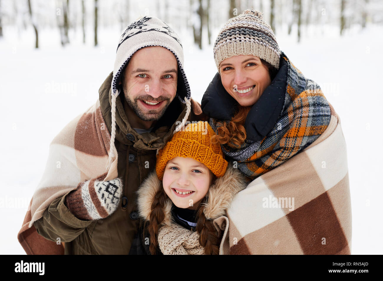 La famiglia felice in posa nella foresta di inverno Foto Stock
