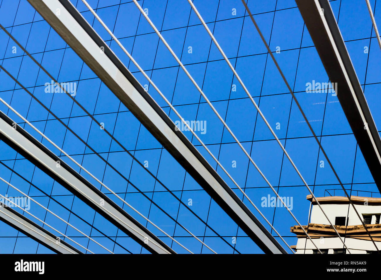 Linee grafiche di travi e cavi in acciaio si fondono con le finestre di un edificio in vetro nel centro finanziario di Rio de Janeiro, Brasile. Foto Stock