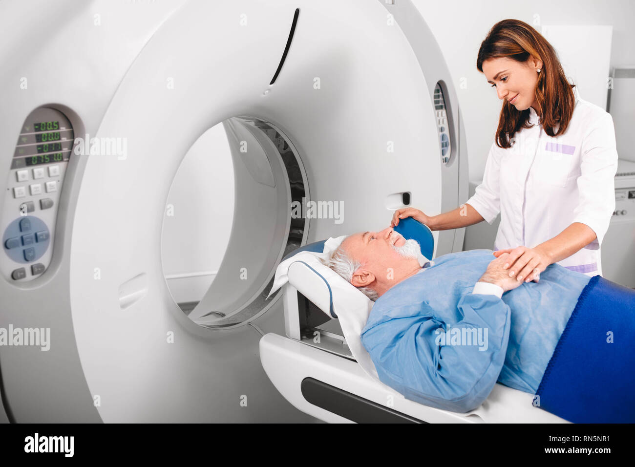 Gentile infermiera preparazione paziente anziano per CT scan in ospedale Foto Stock