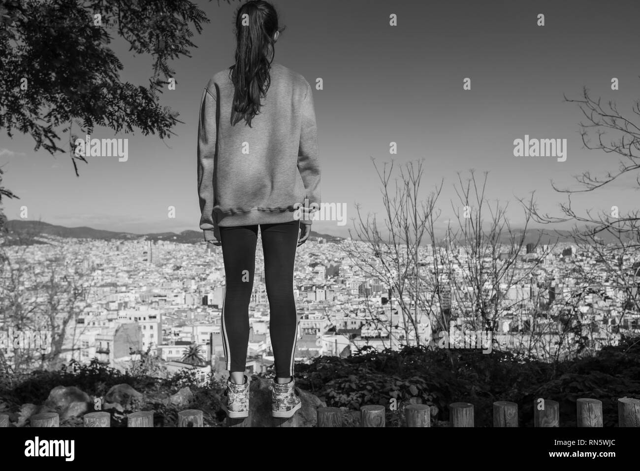 Vista posteriore del giovane ragazza godendo la vista della città di Barcellona da giardini dedicata al poeta Jacinto Verdaguer, Montjuic, Spagna. Foto Stock