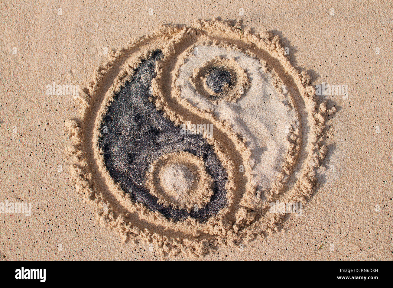 Yin-yang simbolo viene disegnato e riempito con sabbia nera e bianca a Melasti spiaggia di Bali, Indonesia Foto Stock