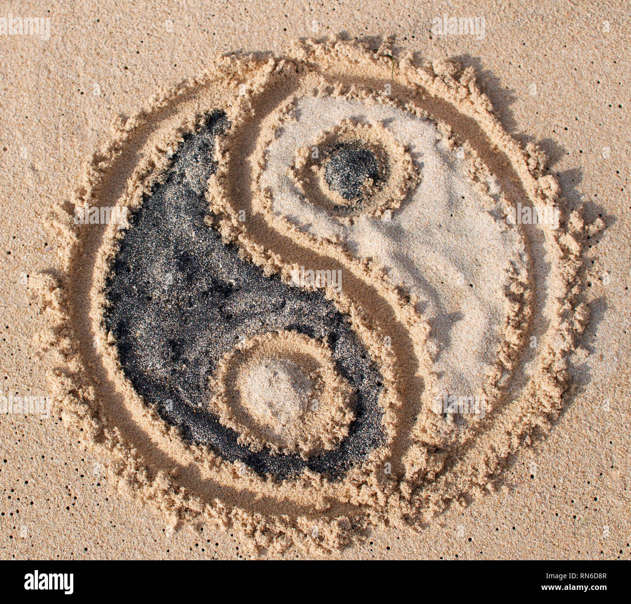 Yin-yang simbolo viene disegnato e riempito con sabbia nera e bianca a Melasti spiaggia di Bali, Indonesia Foto Stock