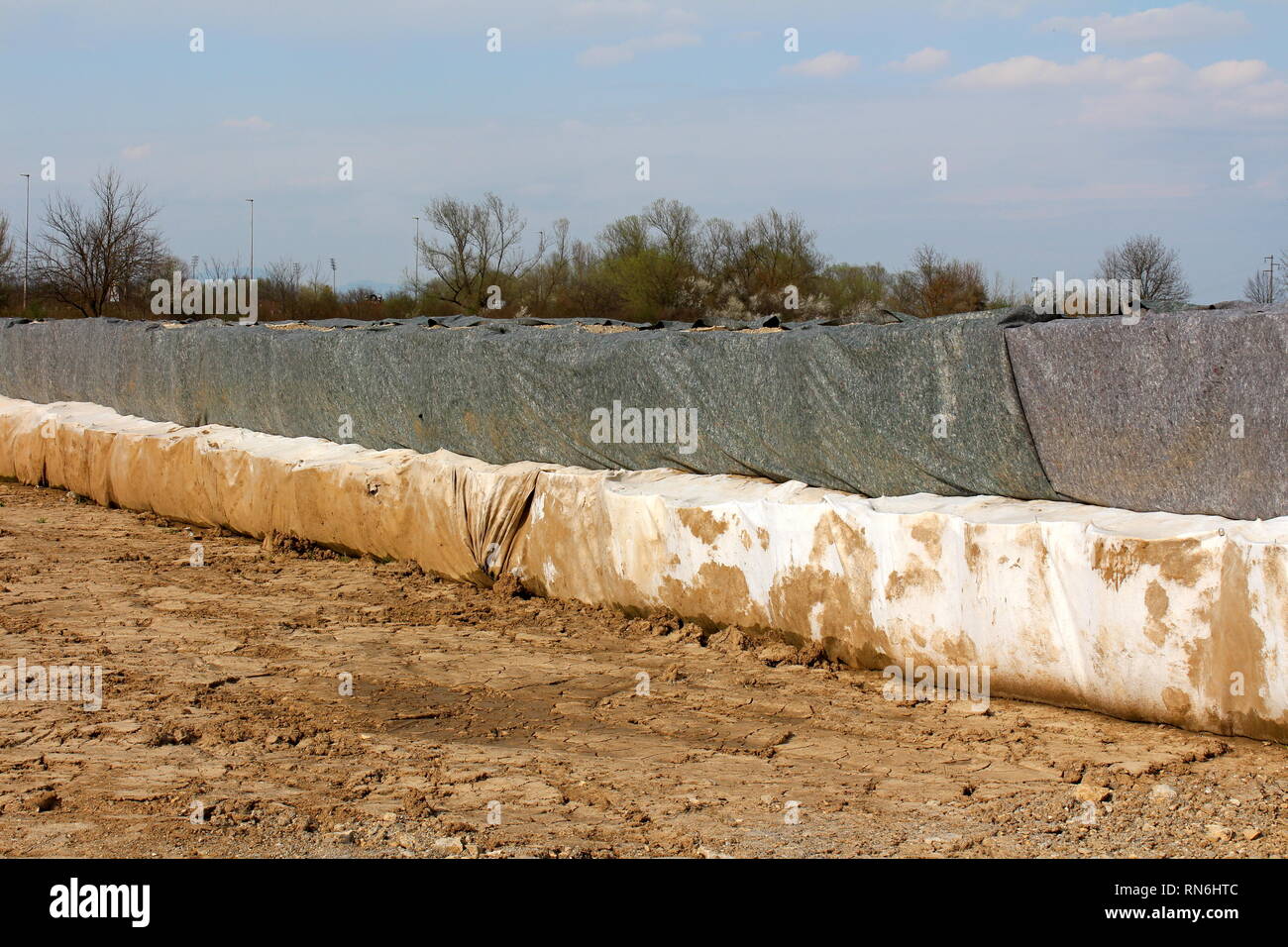 Protezione antiesondazione temporanea di una parete realizzata in due strati di barriere box coperti con il bianco e il grigio panno in geotessile utilizzato per proteggere case famiglia Foto Stock