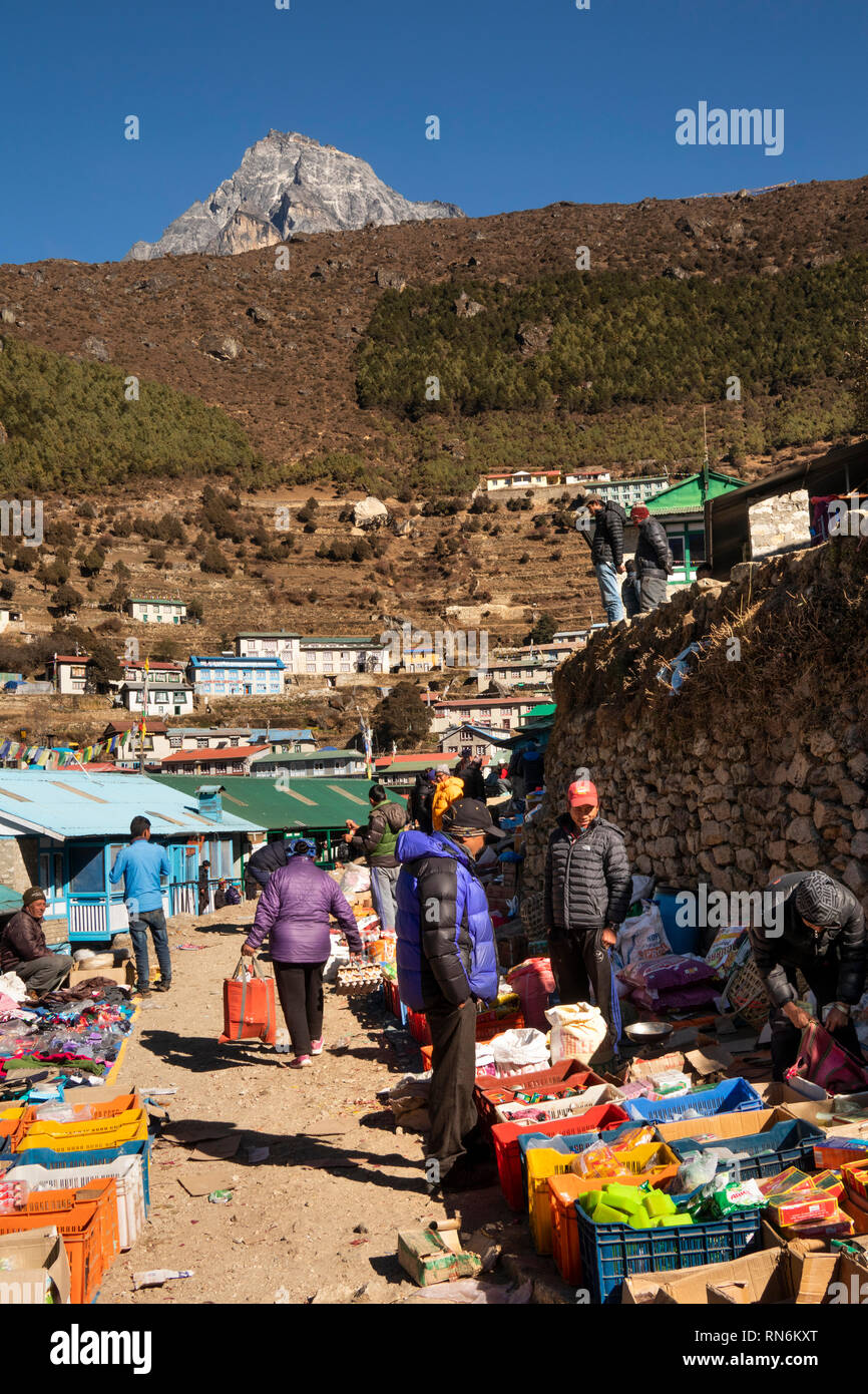 Il Nepal, Namche Bazaar, Mercato, gli acquirenti locali guardando beni domestici visualizzati dal trader in scatole Foto Stock