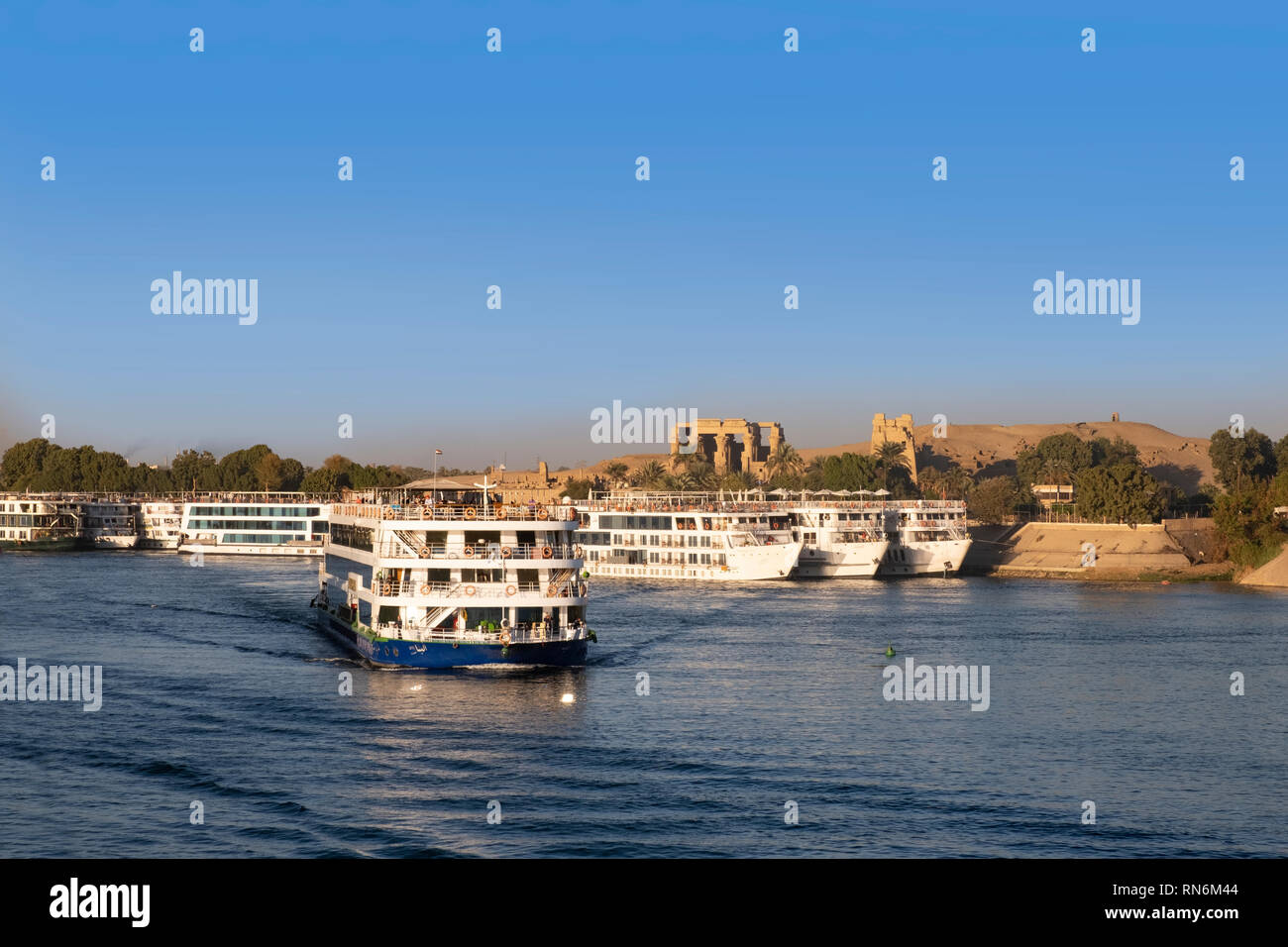 Crociera sul Nilo barca sul fiume con le rovine di Kom Ombo in riverbank Foto Stock