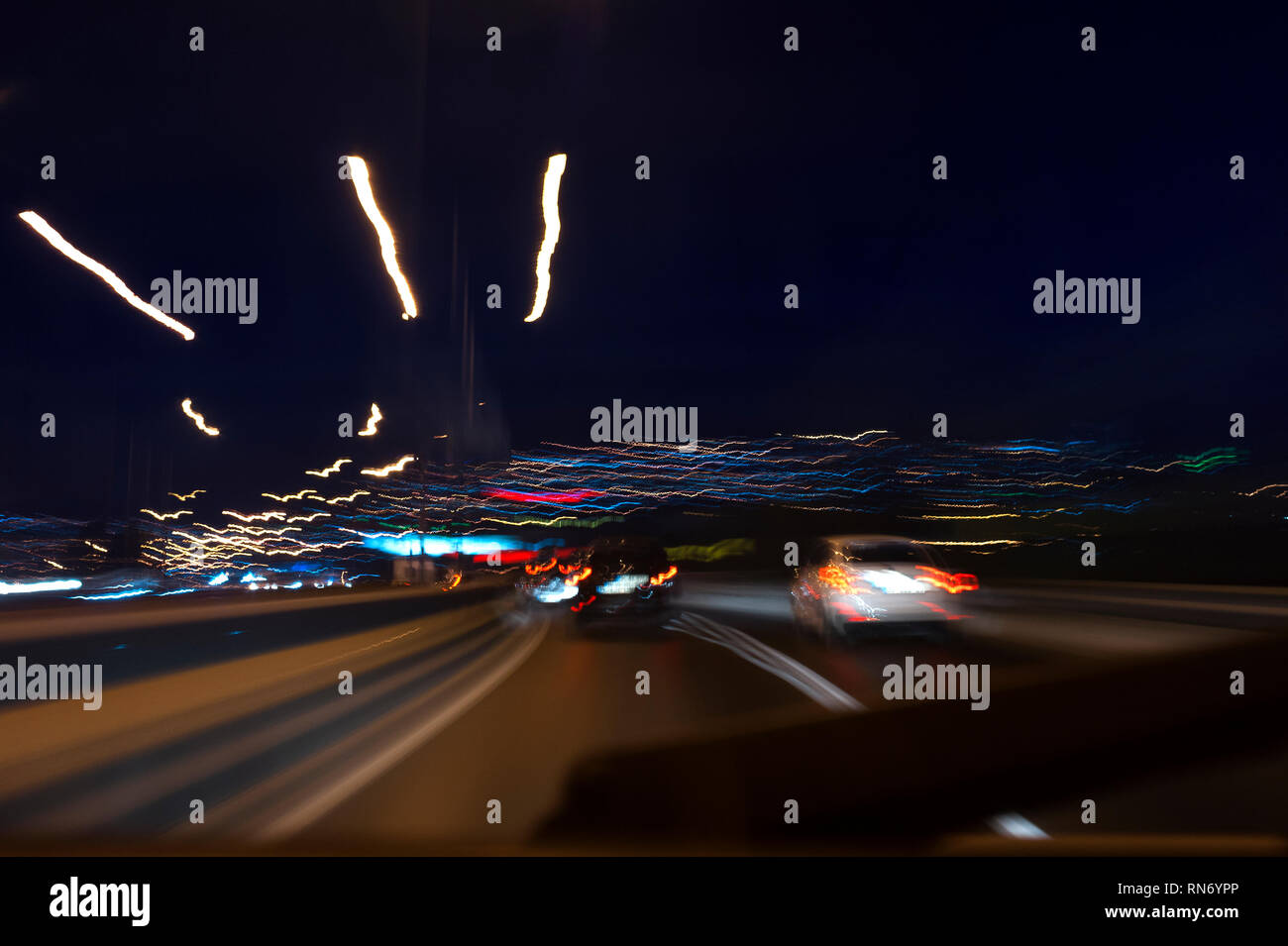 Assomiglia a una vista dagli occhi di un autista ubriaco, lunga esposizione fotografica su strada di notte abstract velocizzando lo sfondo con vetture. Foto Stock