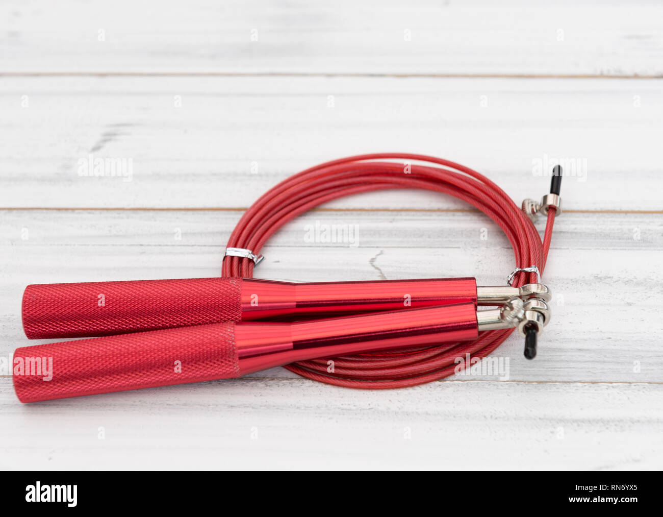 Moderno rosso salto con la corda in bianco sullo sfondo di legno,laici piatta Foto Stock