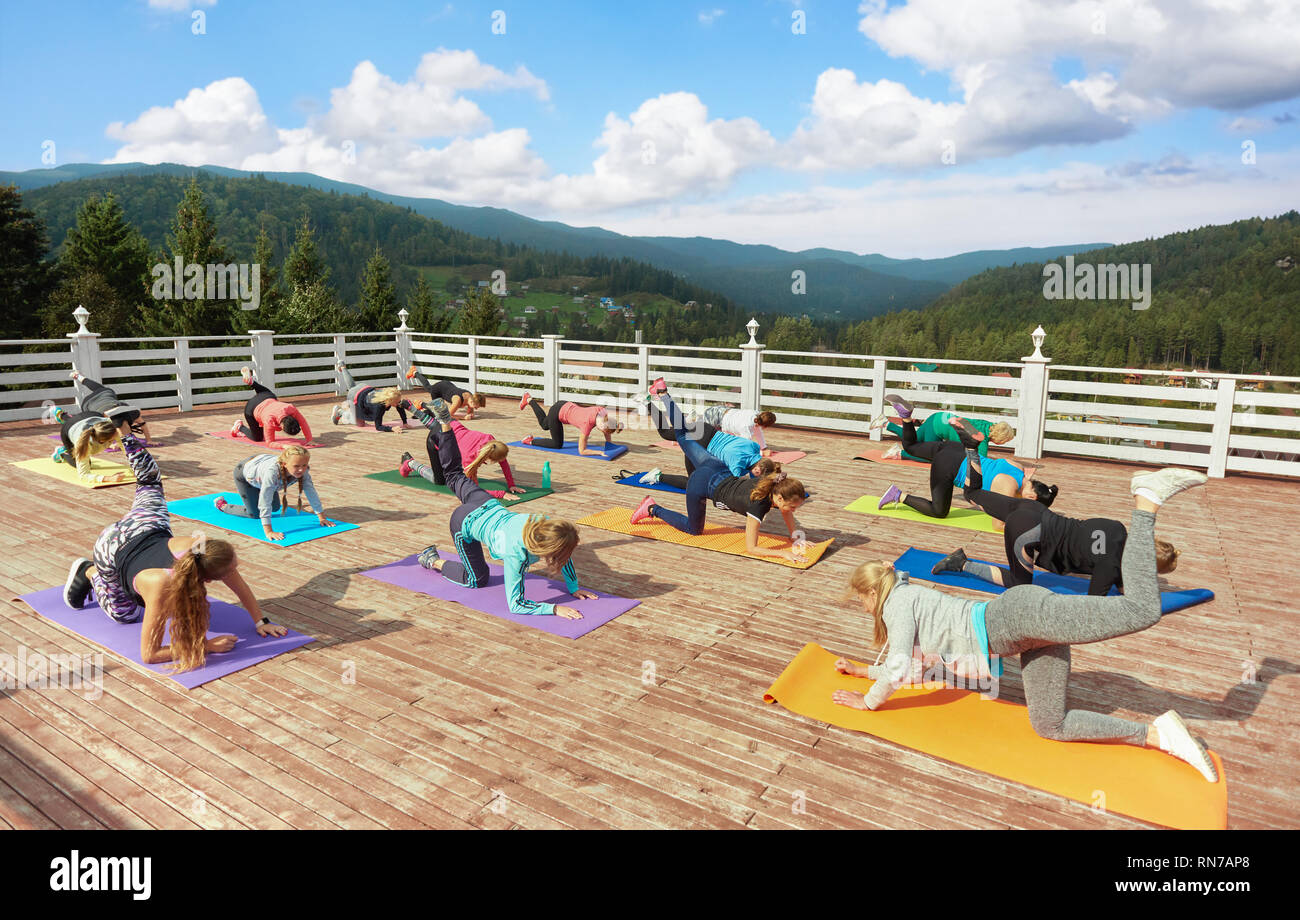 Il gruppo di donne formazione sulla classe di fitness con pullman. Attività sportive e donna sana e le ragazze in piedi sul tavolo posano con gamba sollevata e bilanciamento. Donne praticare su Materassini da yoga. Foto Stock