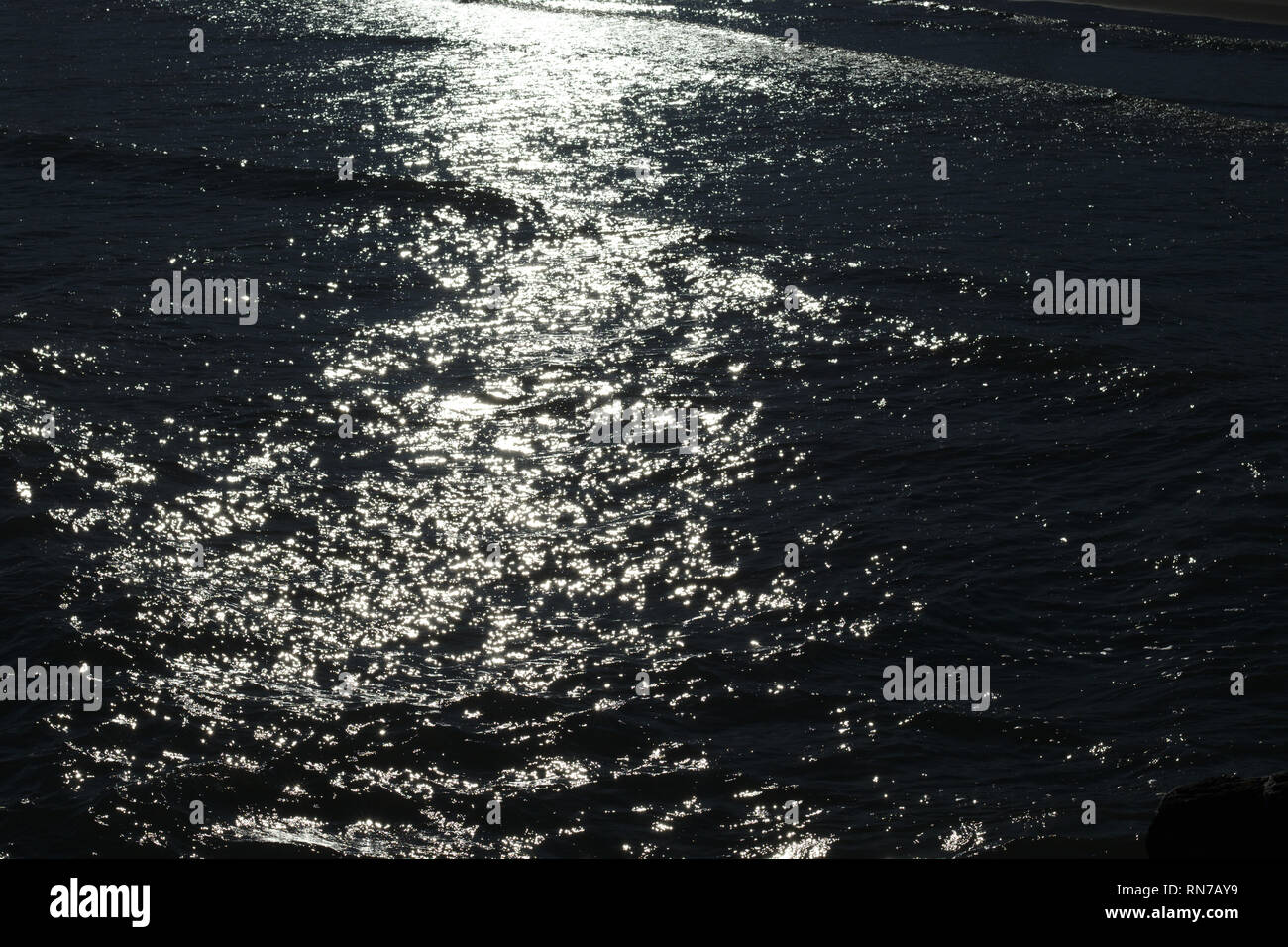 Acqua di mare onde lentamente sotto l'ultima luce solare produrre bei modelli. Foto Stock