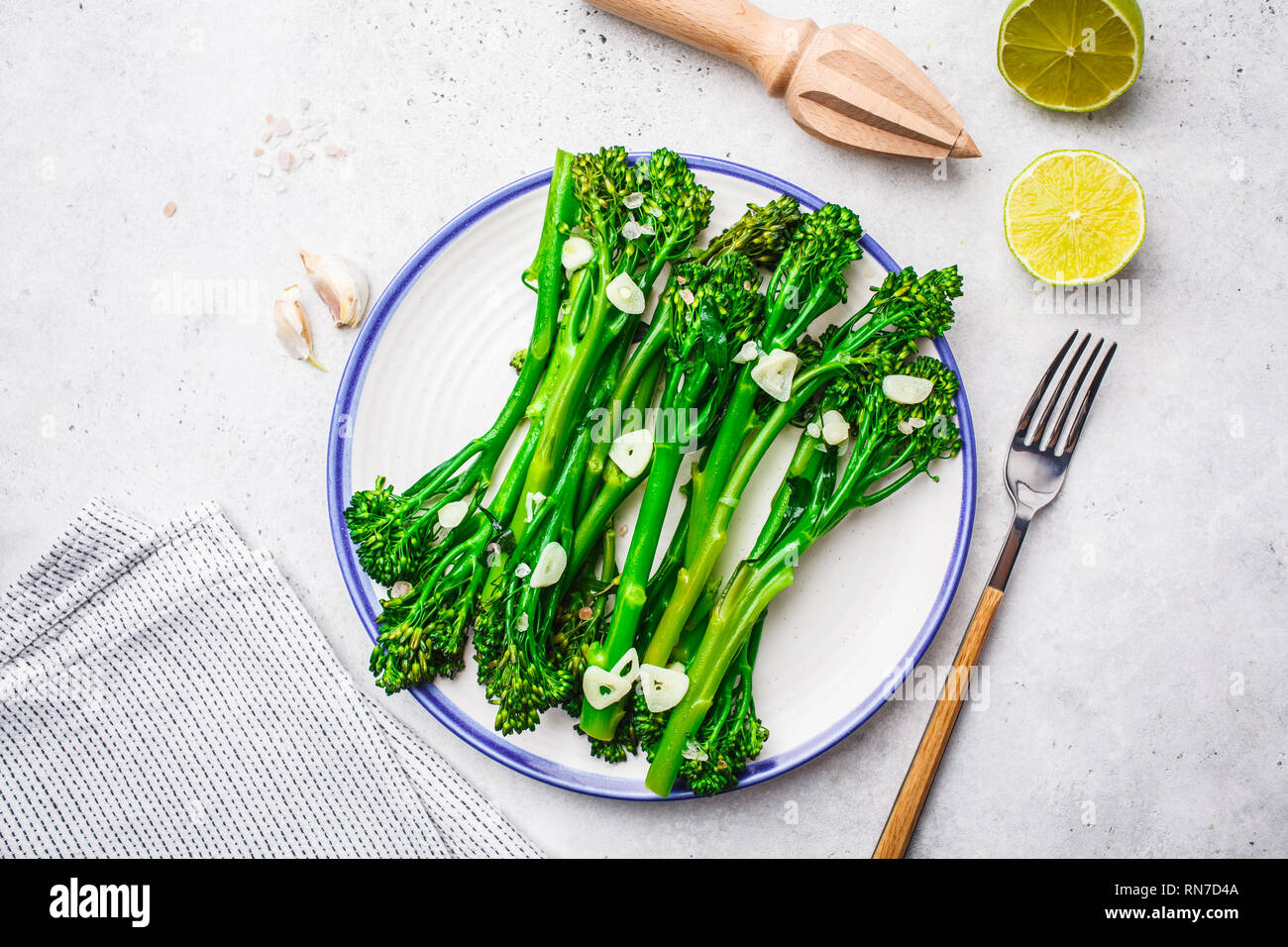 Broccolini bollito con aglio su una piastra bianca. Impianto basato il concetto di cibo. Foto Stock
