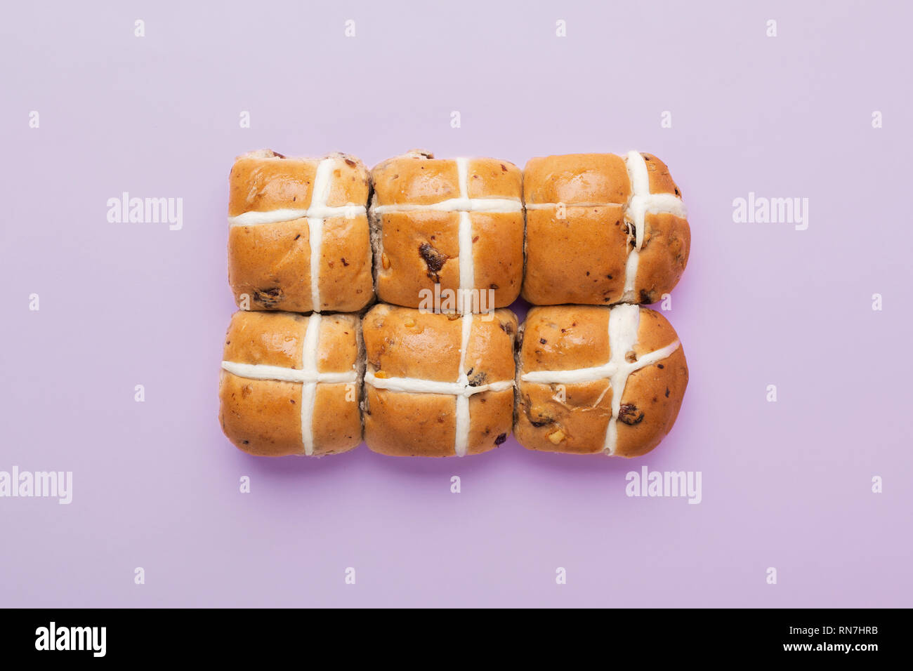 Sei hot cross panini, britannica tradizionale cibo Pasqua sul pastello sfondo lilla, vista dall'alto, il fuoco selettivo Foto Stock