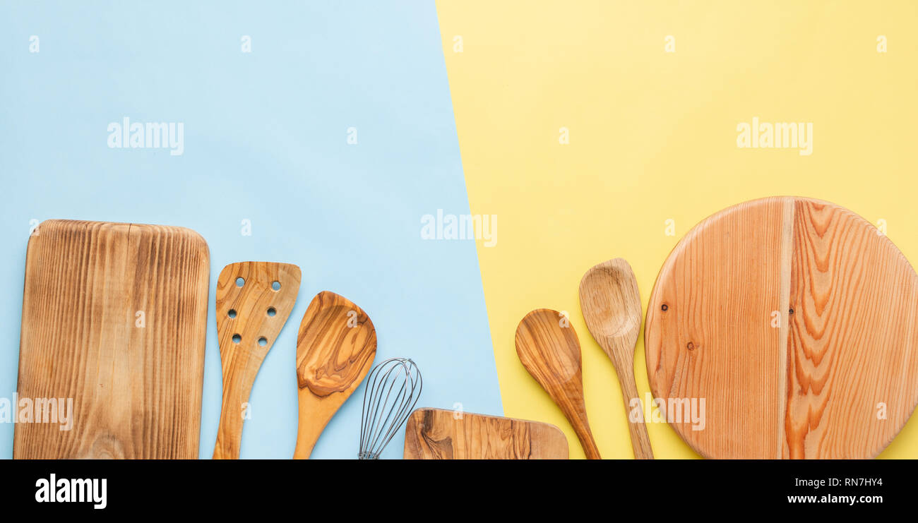 Utensili da cucina, per la preparazione di alimenti accessorises cottura, taglieri, mestoli, frusta sul blu e giallo tabella, vista dall'alto, il fuoco selettivo Foto Stock