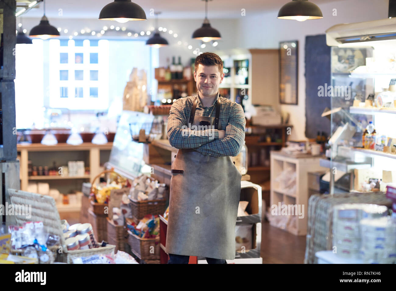 Ritratto del maschio sorridente Proprietario del negozio delicatessen indossando il grembiule Foto Stock