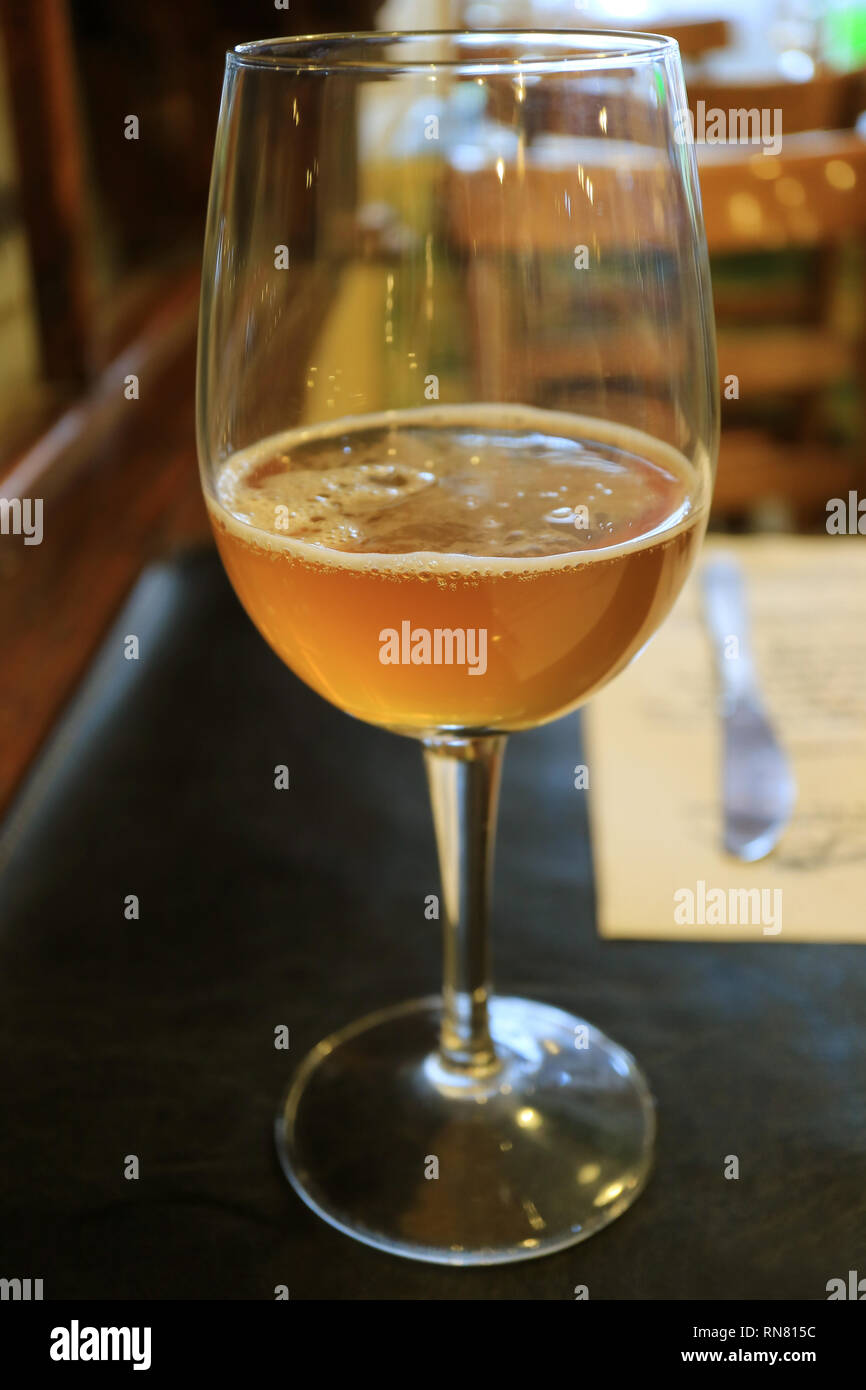 Un vetro di colore oro refrigerate birra artigianale su un tavolo da pranzo Foto Stock