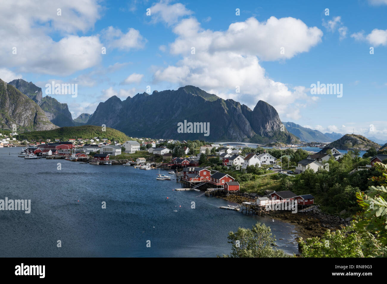 Vista spettacolare delle isole Lofoten in Norvegia paesaggio vista del villaggio di pescatori con le montagne, acqua e cielo blu. Foto Stock
