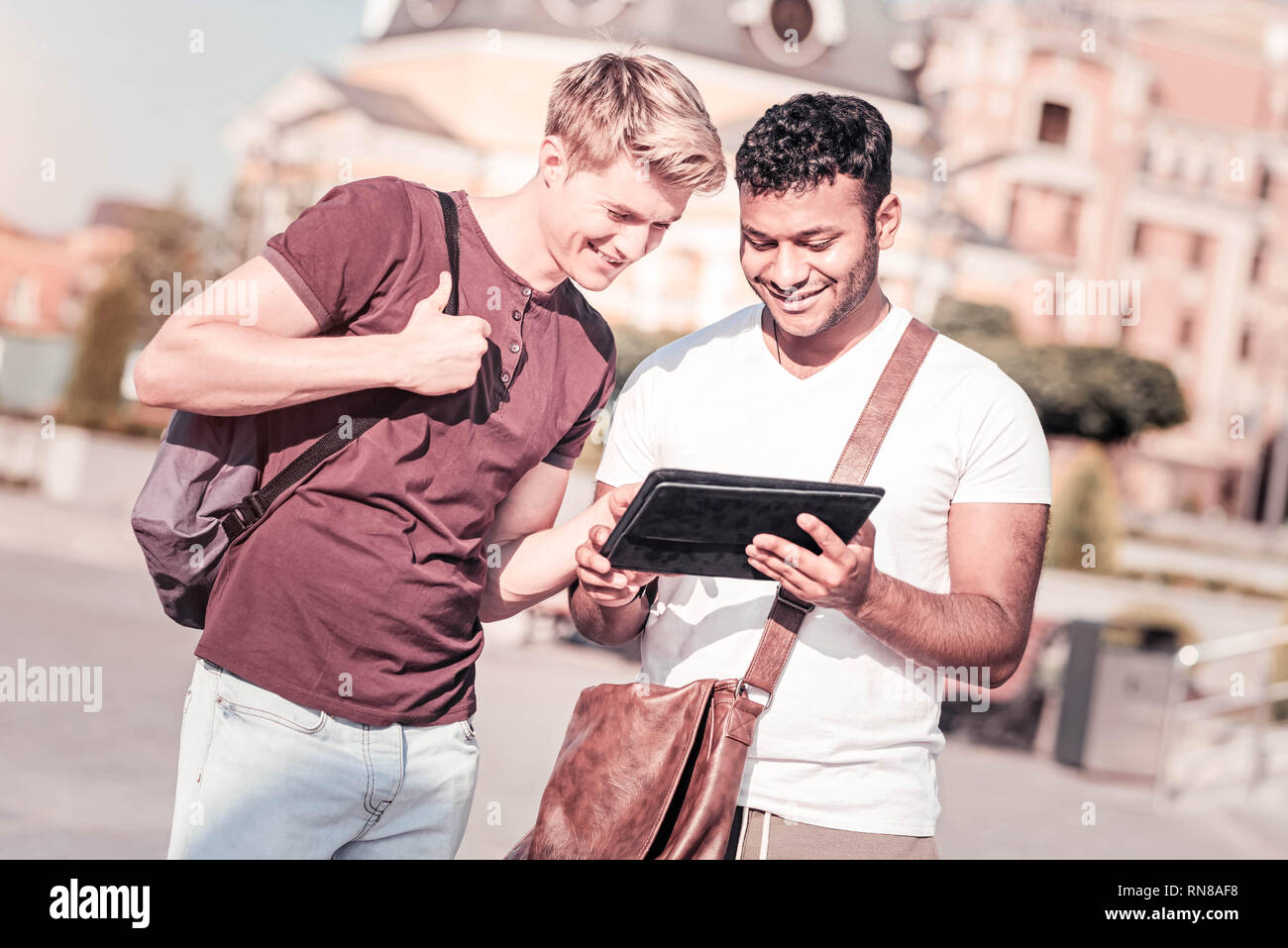 Mostra a me. Positivo maschi piacere guardando lo schermo del tablet e mantenendo il sorriso sui volti durante la preparazione per la presentazione Foto Stock