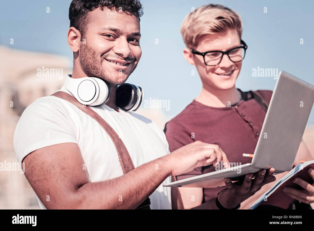 Express positività. Allegro brunette mantenendo il sorriso sul suo volto e utilizzo di computer portatile mentre guardando la fotocamera Foto Stock