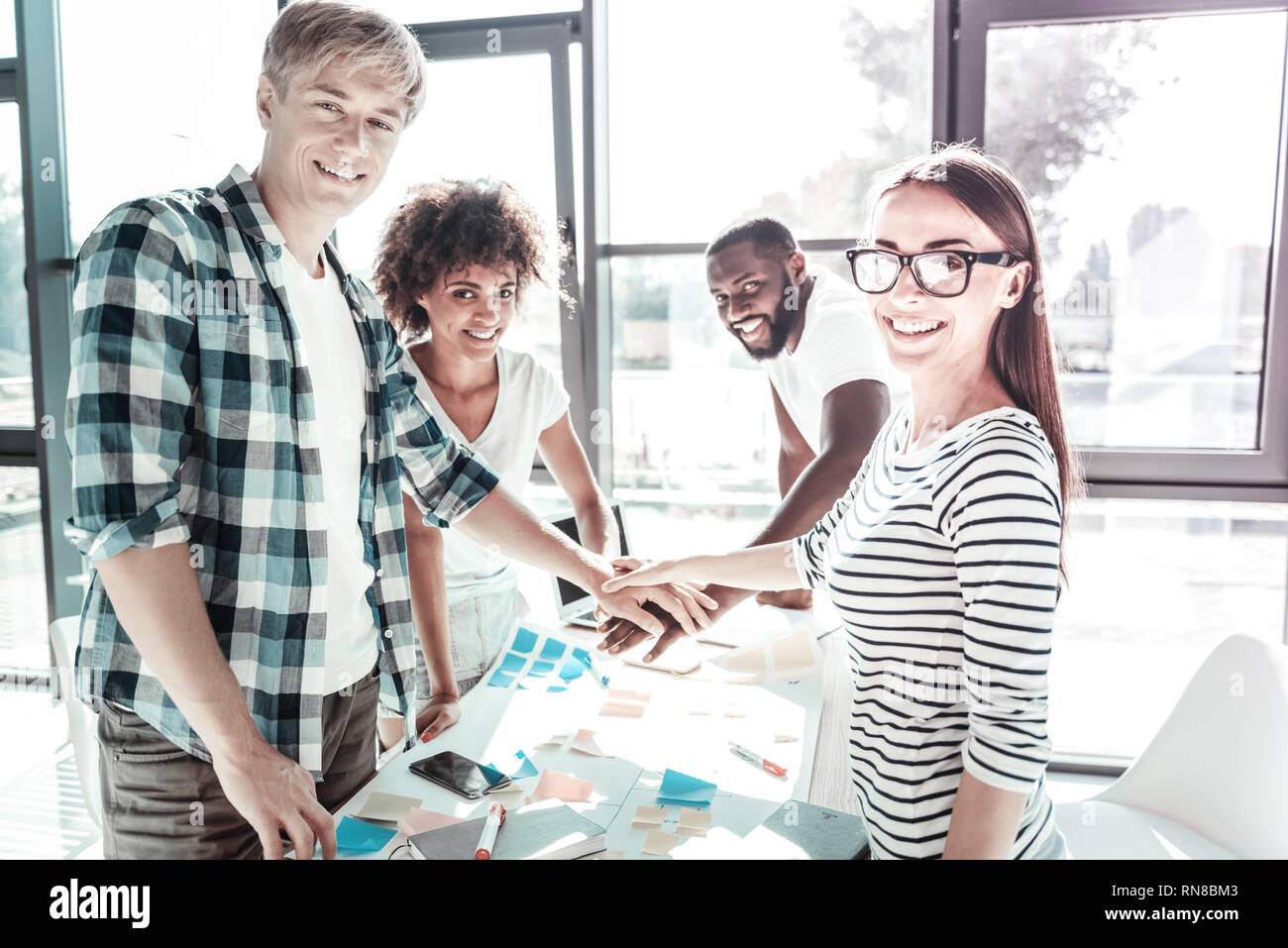 Express positività. Felici i giovani mantenendo sorrisi sui volti e tenendo le mani insieme mentre guardando la fotocamera Foto Stock