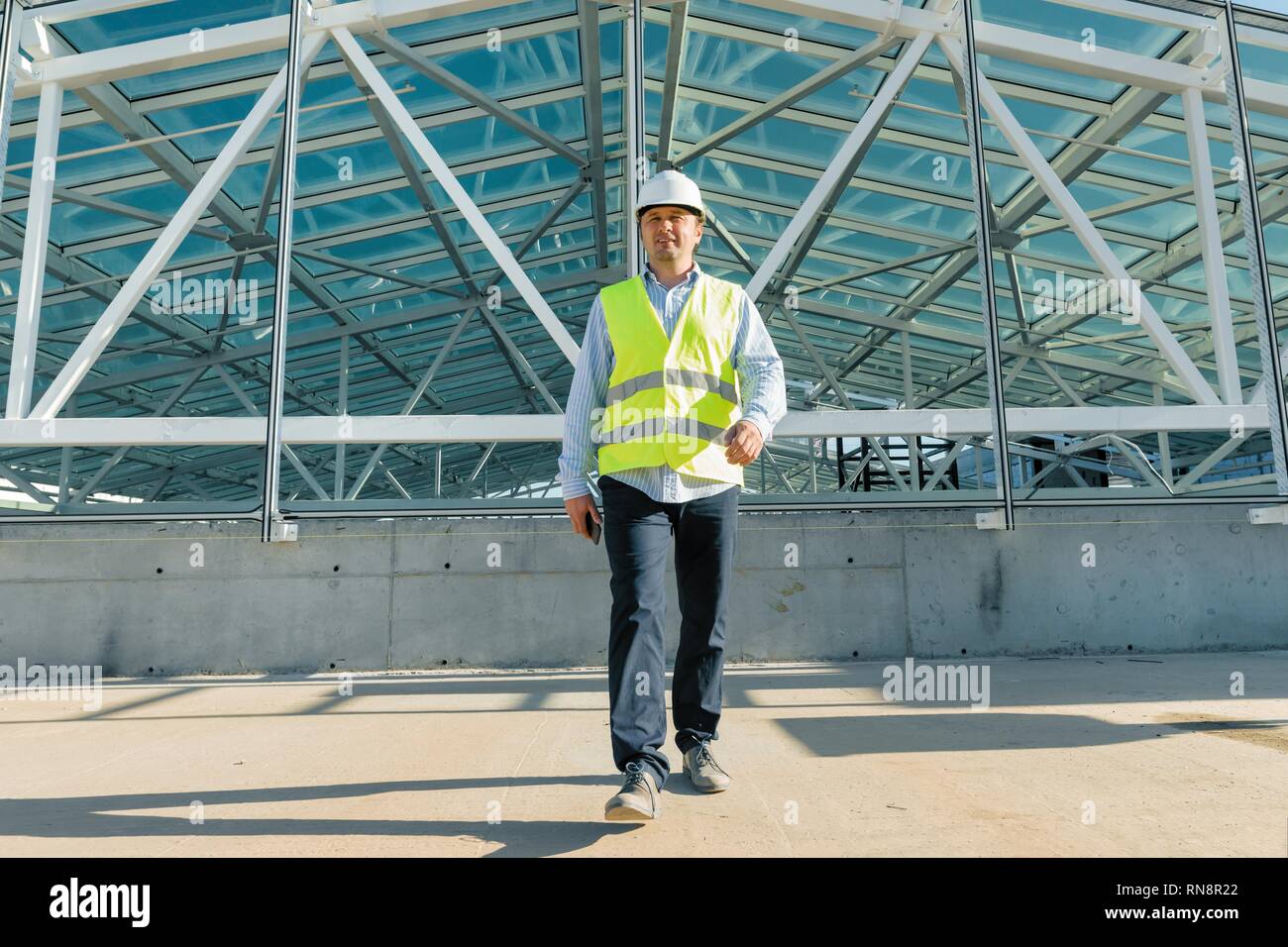 Builder maschio a camminare in avanti sul tetto del sito in costruzione. Building e di sviluppo concetto. Foto Stock