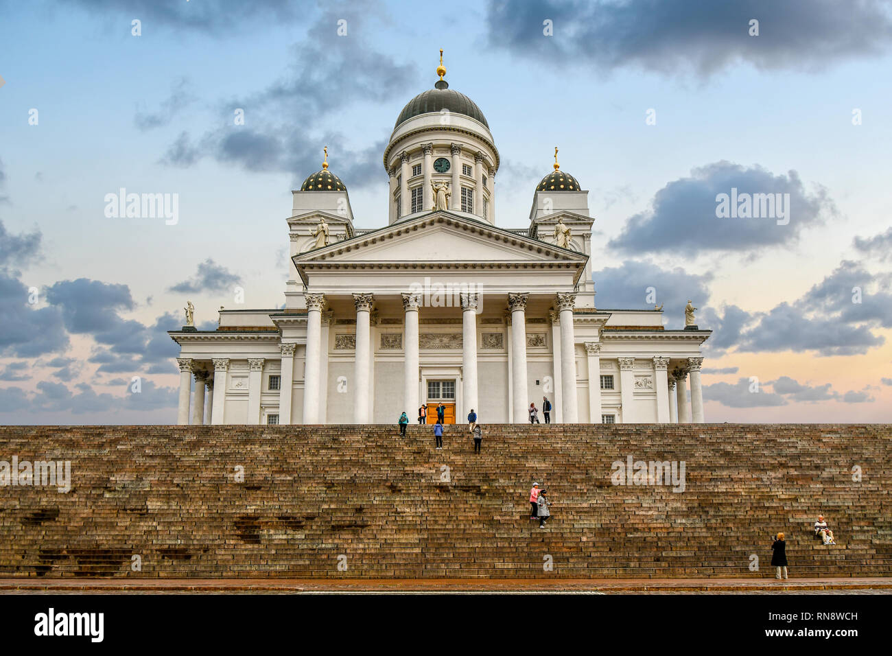 I turisti che visitano la Piazza del Senato, stando in piedi sui gradini della neoclassica Cattedrale di Helsinki nel centro della città di Helsinki, Finlandia. Foto Stock