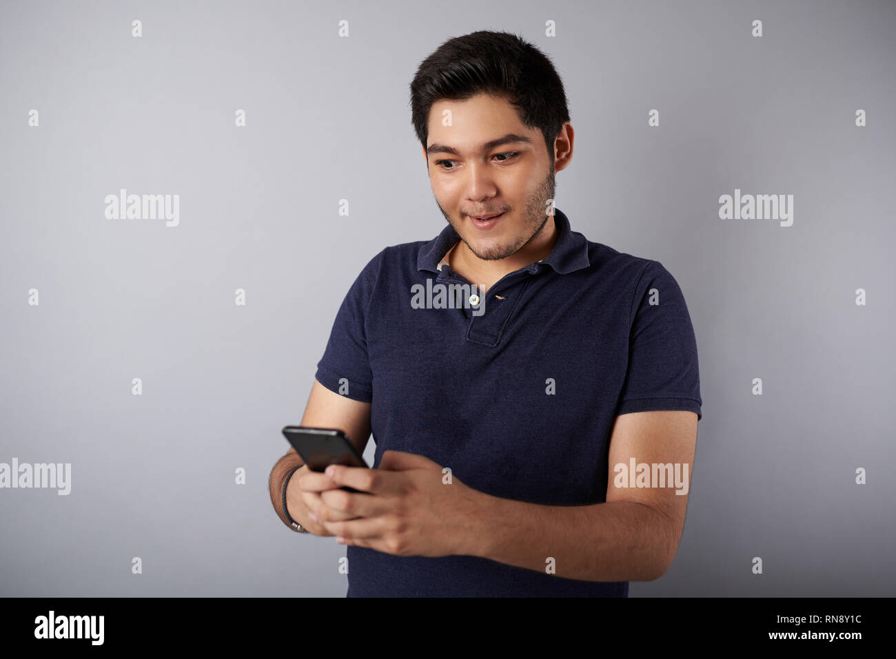 Fake Tema notizie. Giovane uomo sorpreso dopo la lettura di smartphone Foto Stock