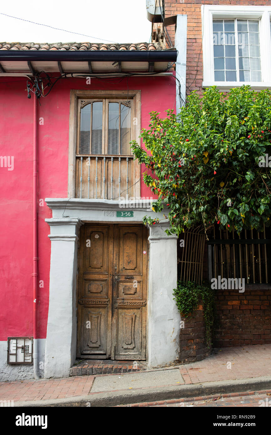 Luminosa facciata in stile coloniale dell'edificio con la vecchia porta di legno. La Candelaria, Bogotà, Colombia. Sep 2018 Foto Stock