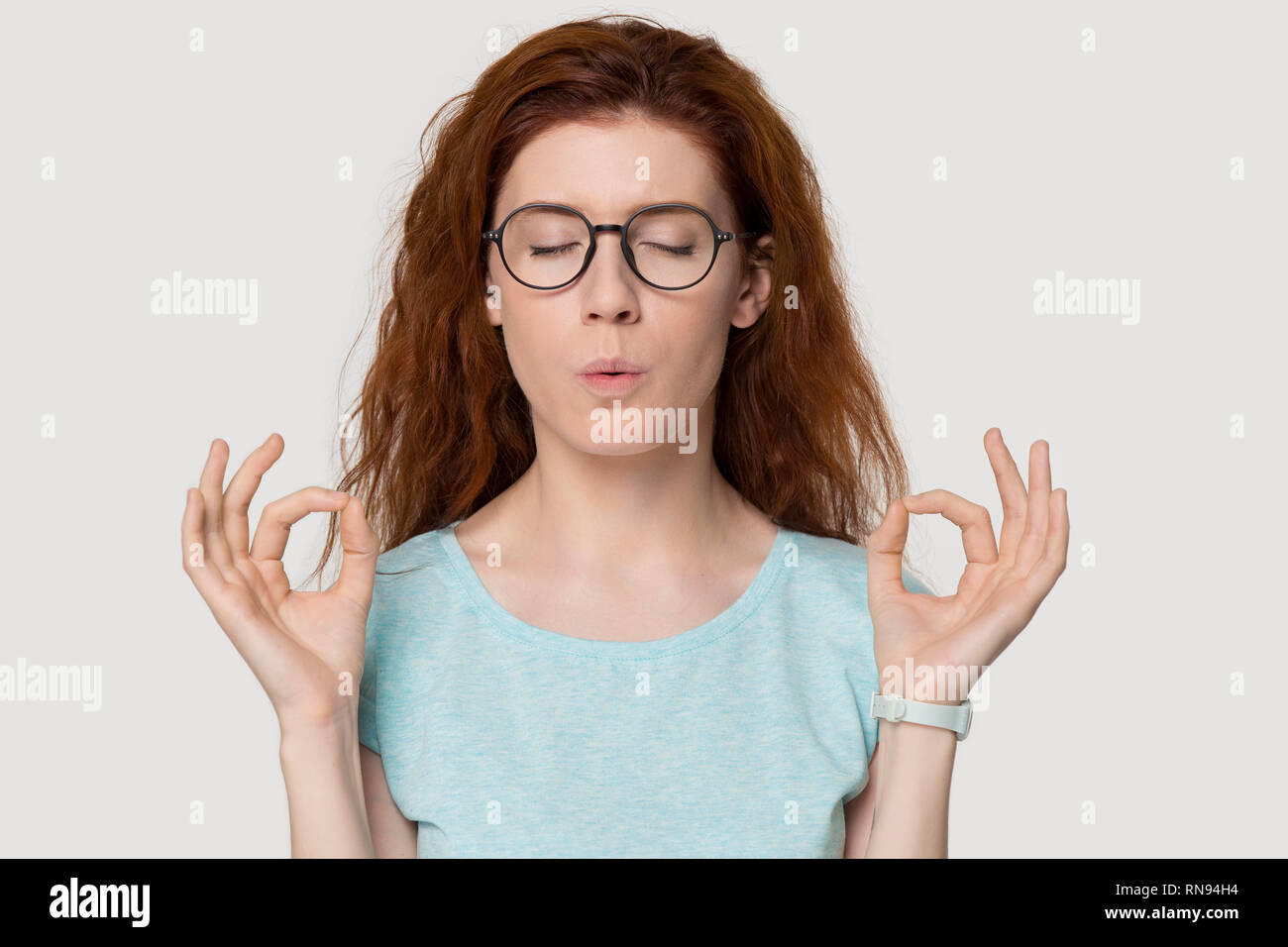 Sottolineato redhead donna meditando alleviare lo stress facendo esercizi di respirazione Foto Stock