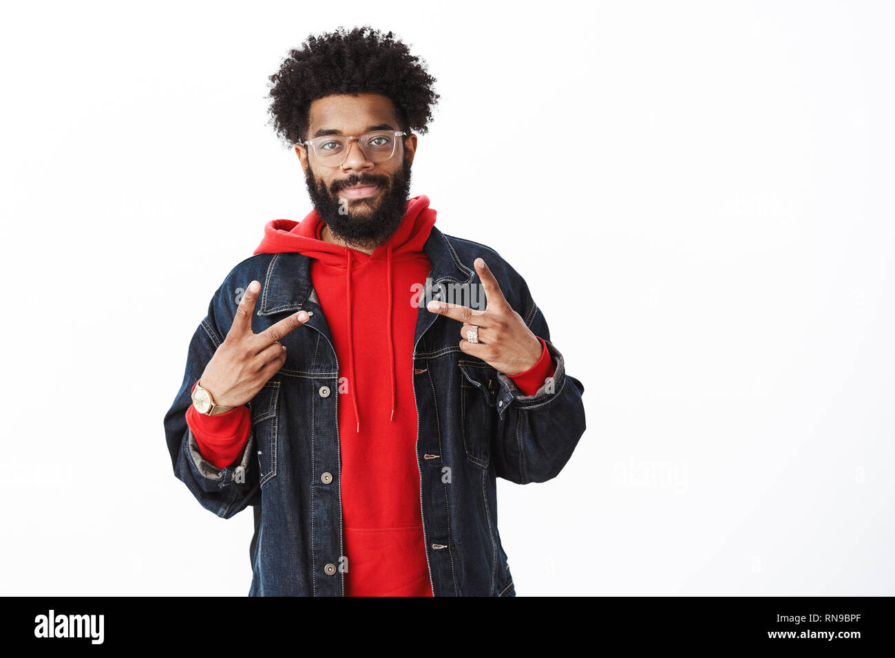 Vita-up shot di soddisfatti e cordiale sorridente americano africano uomo  barbuto con acconciatura afro in bicchieri, denim camicia al di sopra felpa  con cappuccio rosso grinning a Foto stock - Alamy