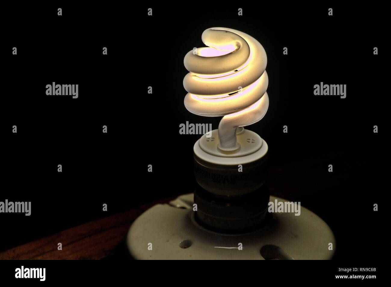Una lampada compatta a fluorescenza in una presa di luce accesa. Foto Stock