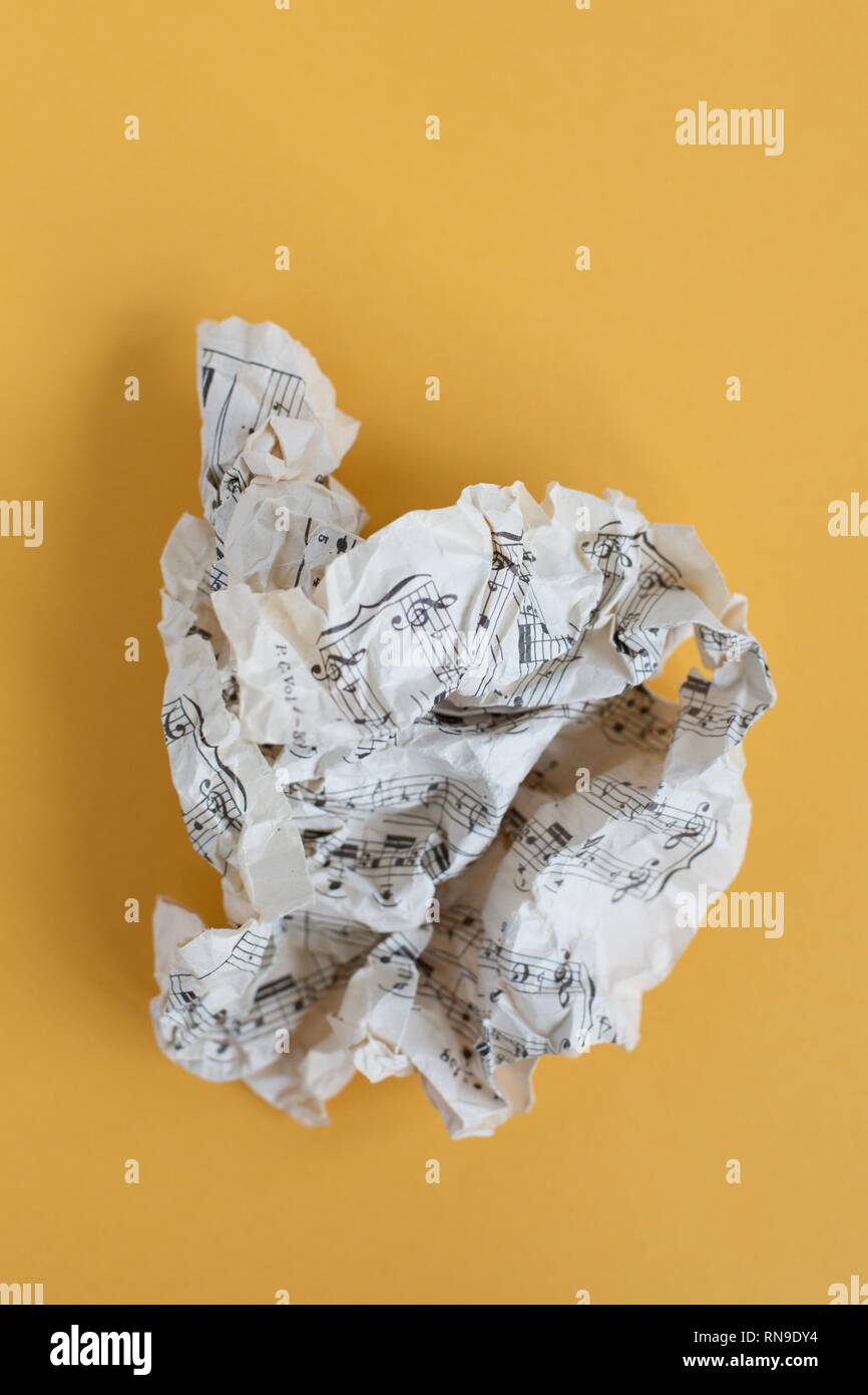 Crumpled sheet music pianura su sfondo giallo. Foto Stock