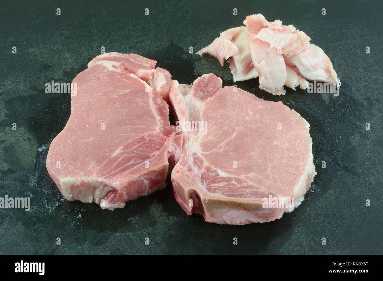 Due materie a taglio centrale osso in costolette di maiale con un eccesso di grasso tagliato su nero tagliere per un sano abbassare il colesterolo pasto Foto Stock