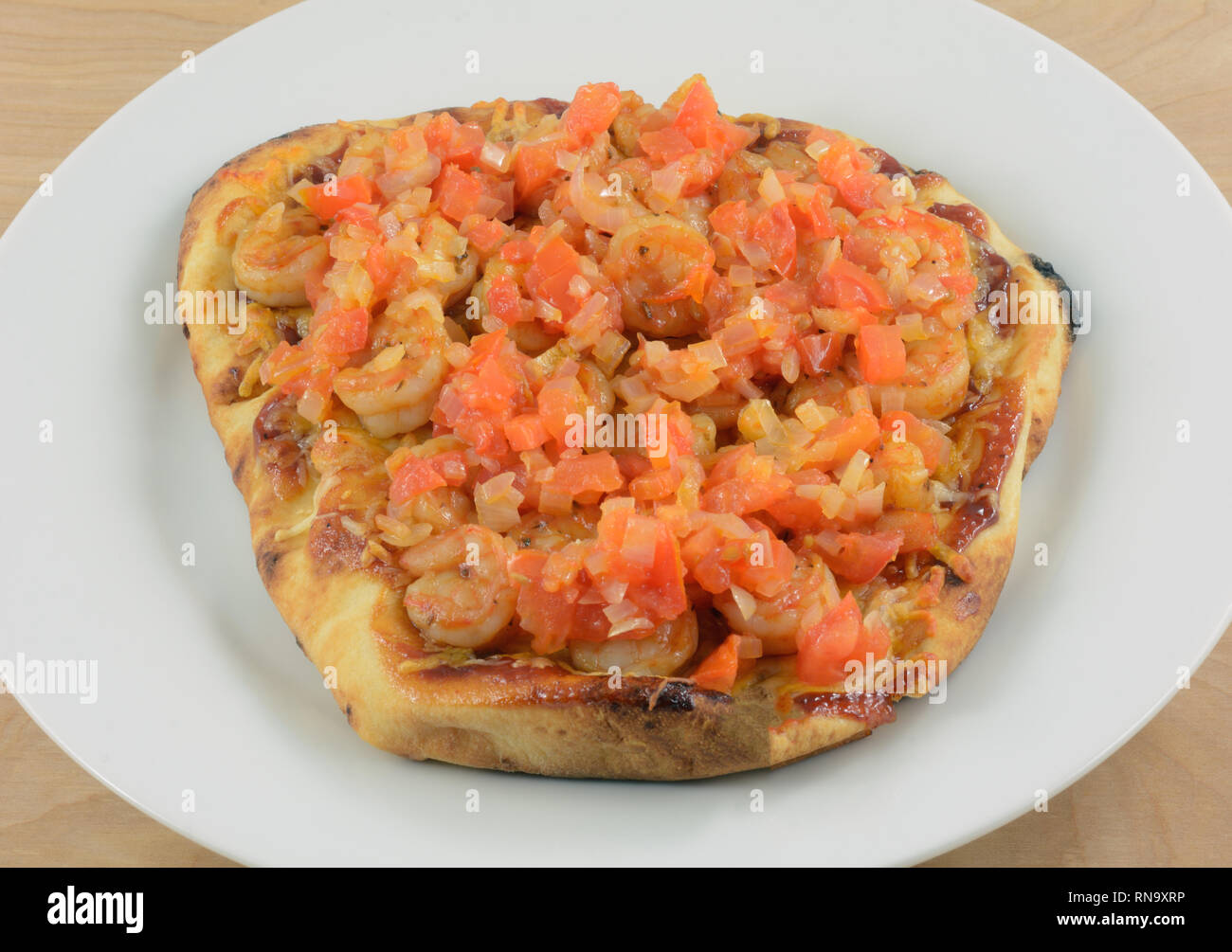 Pane Naan gamberetti pizza con formaggio e pomodori tagliati su piastra bianca Foto Stock
