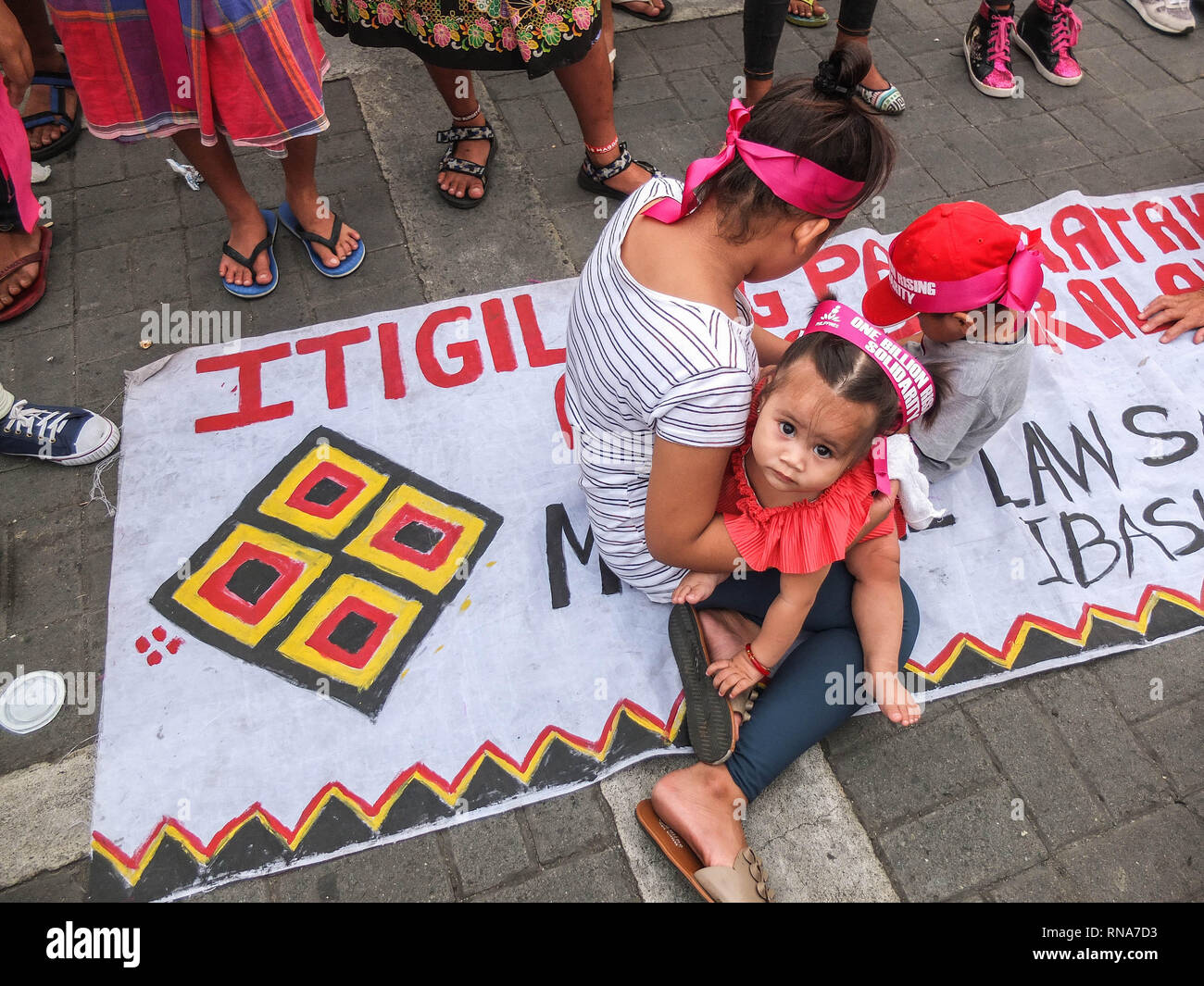 Una madre e il suo bambino seduto in uno streamer a unirsi a un miliardo di evento in salita. Persone di tutti i ceti sociali, raccoglie a Rajah Sulayman Park a unirsi a un miliardo di crescente solidarietà evento, un advocacy chiamando per fermare la violenza contro le donne e i bambini. Foto Stock