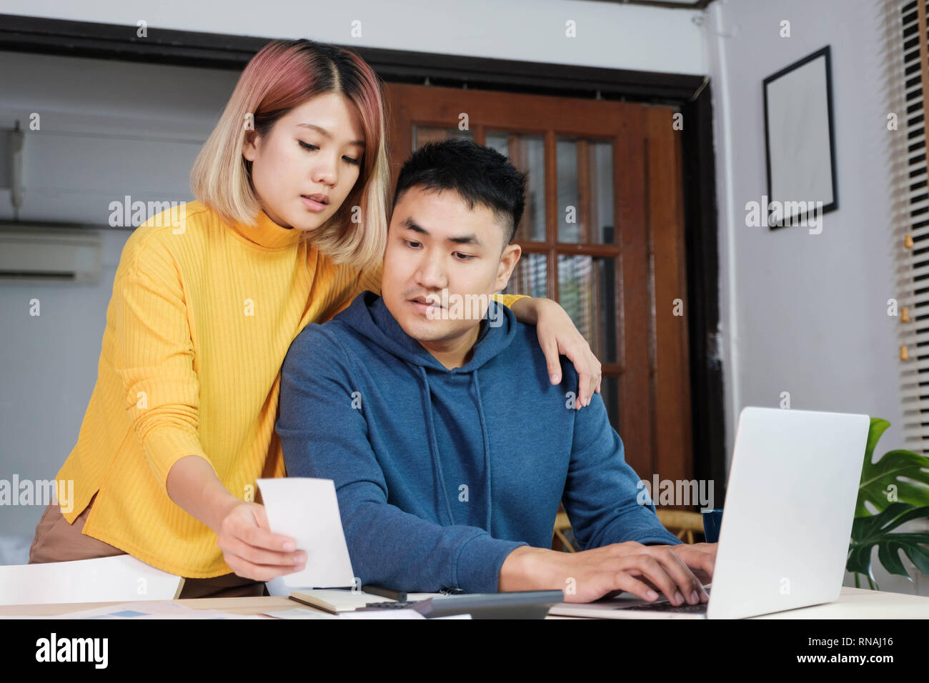 Asian coppia insieme calcolare home budget con la carta bill e laptop nella nuova casa a tavola in cucina Foto Stock