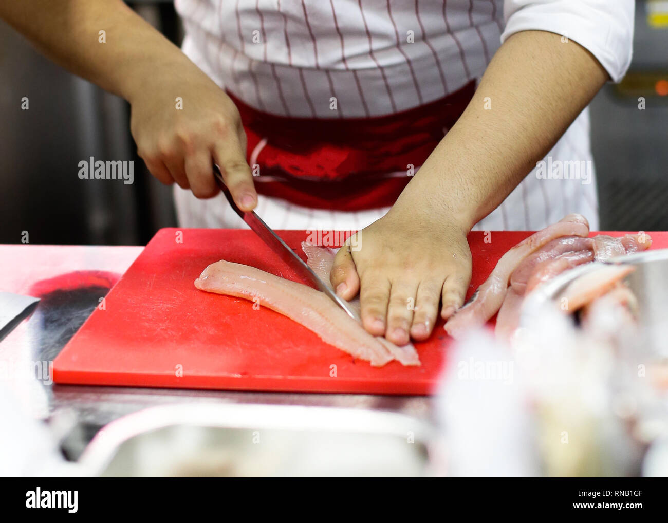 Tagliare il filetto di pesce in una pescheria, chef di pesce di taglio in  cucina Foto stock - Alamy